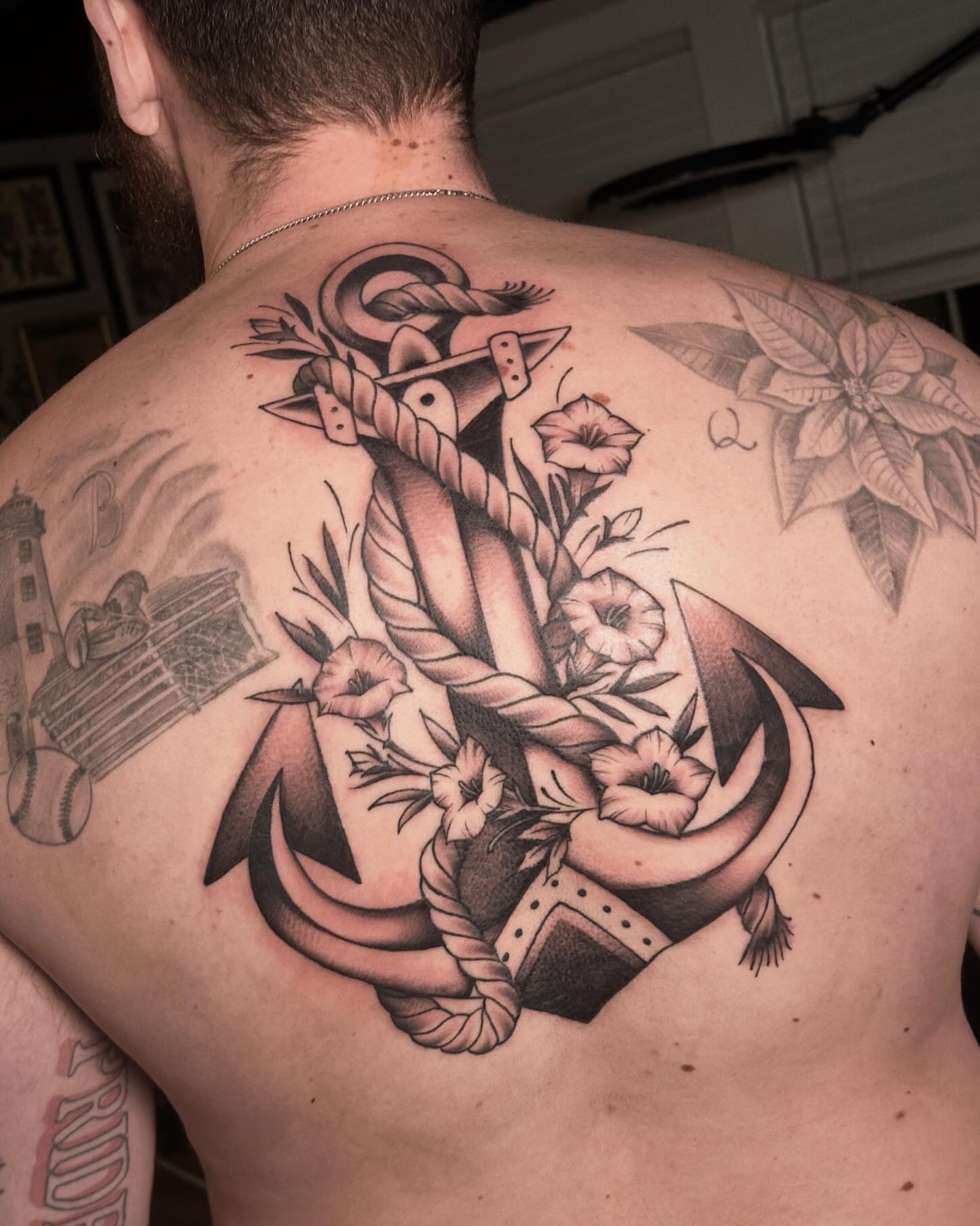 Anchor with flowers black and grey tattoo on the back by Craig Ryans