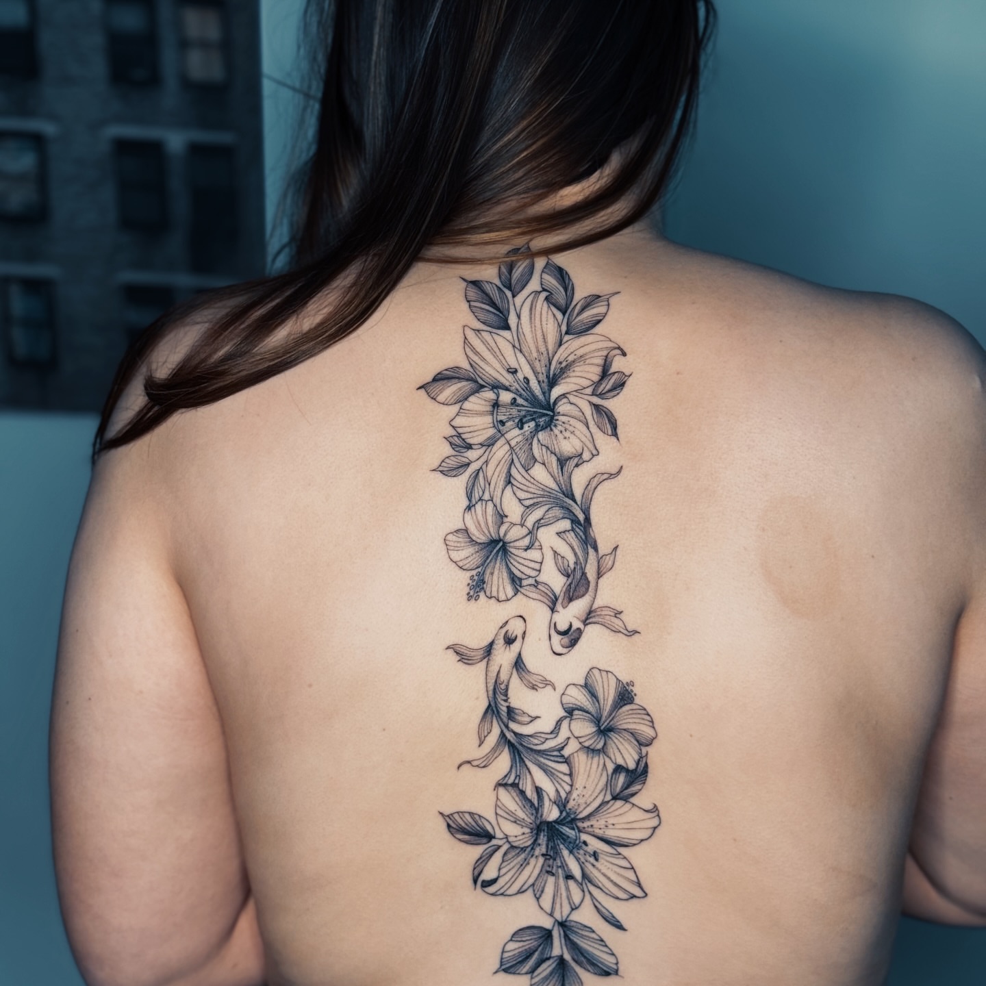 Flowers and fish black and grey tattoo on the back by Olha Tytarenko