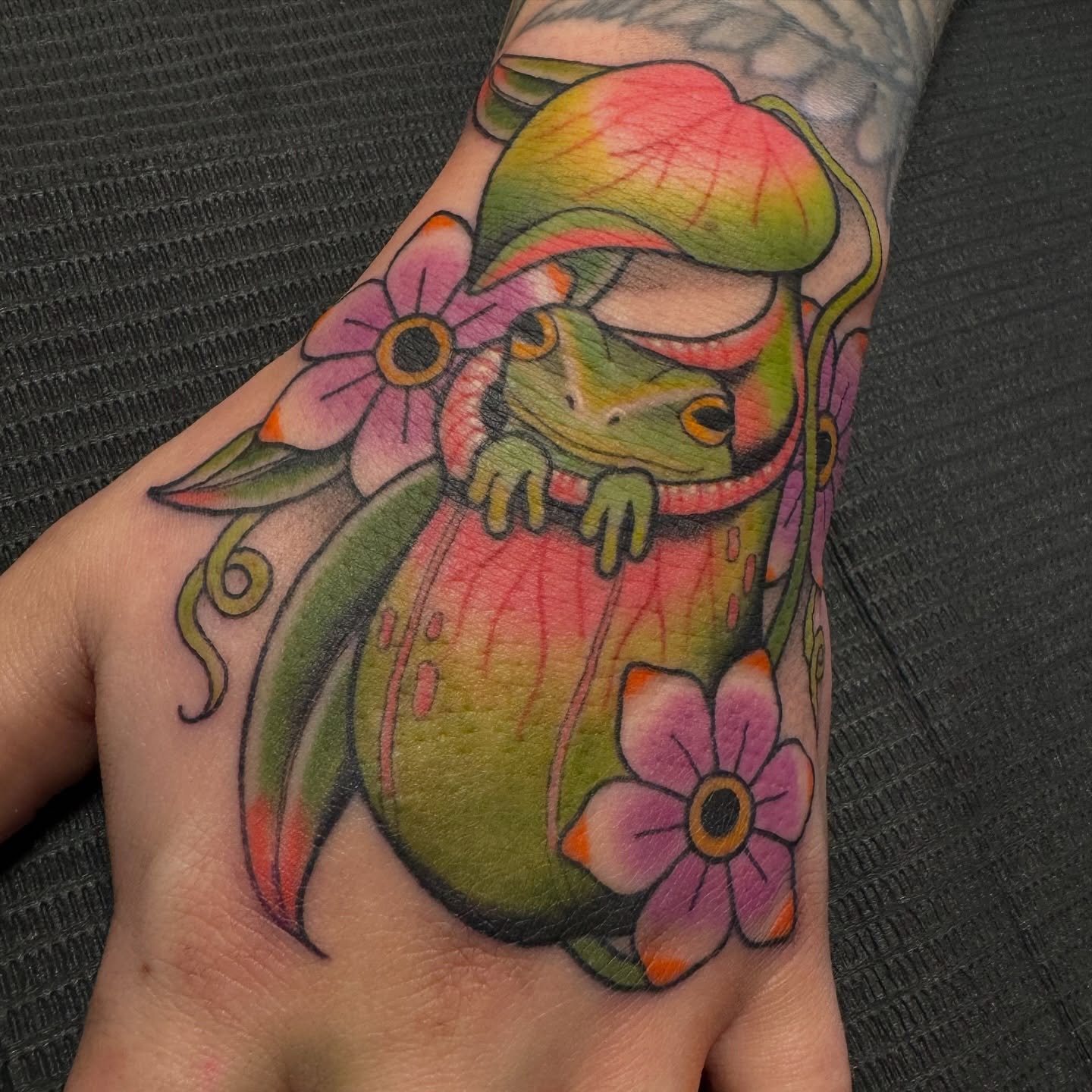 Frog and flowers new school tattoo on the hand by Kaley, Des Moines, Iowa