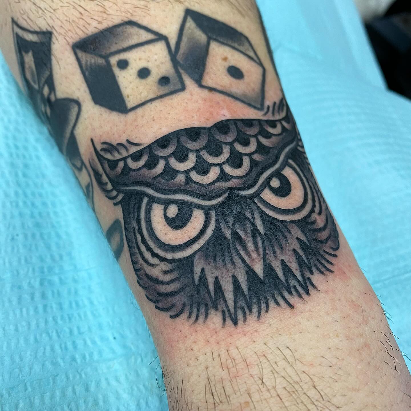 Owl black and grey tattoo on the forearm by Tom Wenzell