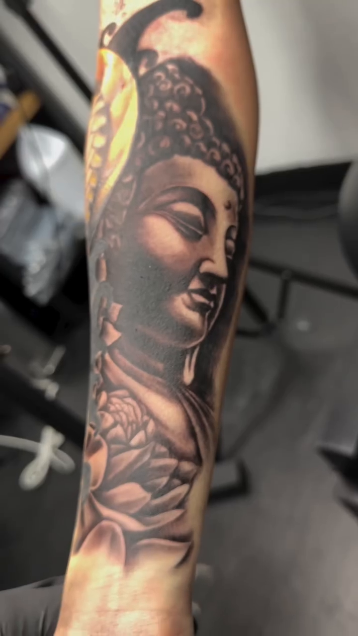 Buddha head with lotus flowers realism tattoo by Ricky Flemate, San Antonio