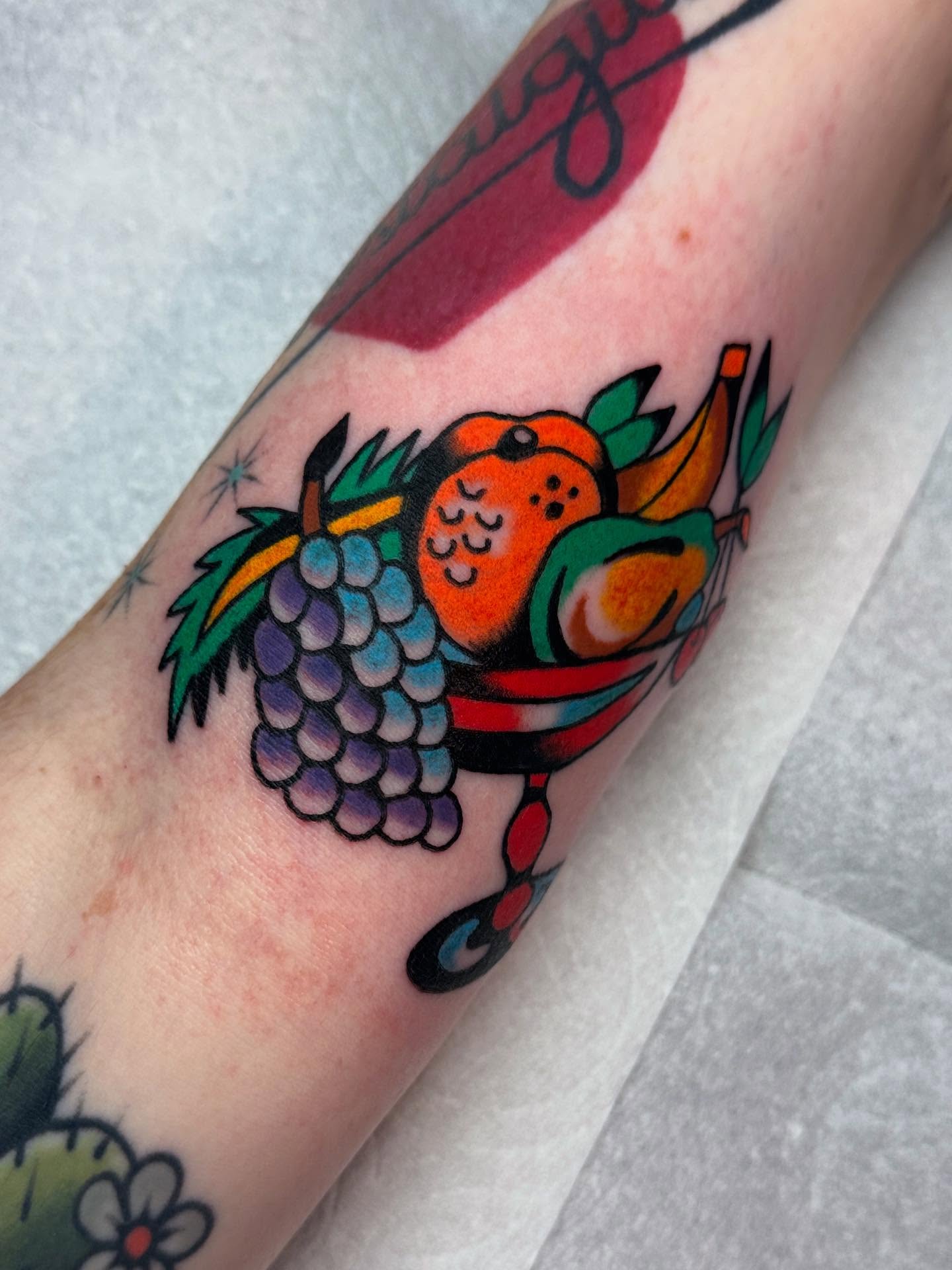 Parrot and grapes American traditional tattoo on the forearm by Britt Kuechenmeister, Culver City, California