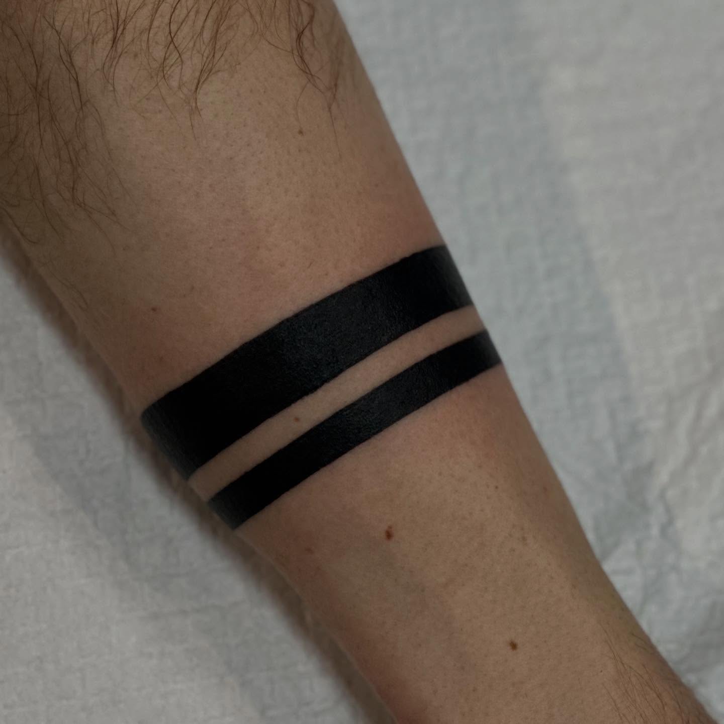 Horizontal stripes minimalist tattoo on the forearm by Dylan Curry