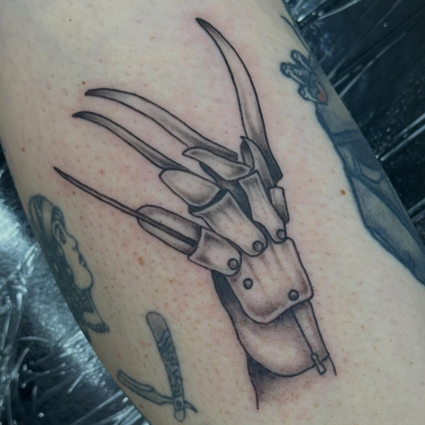 Fingers with knives black and grey tattoo on the forearm by Olivia Norbert