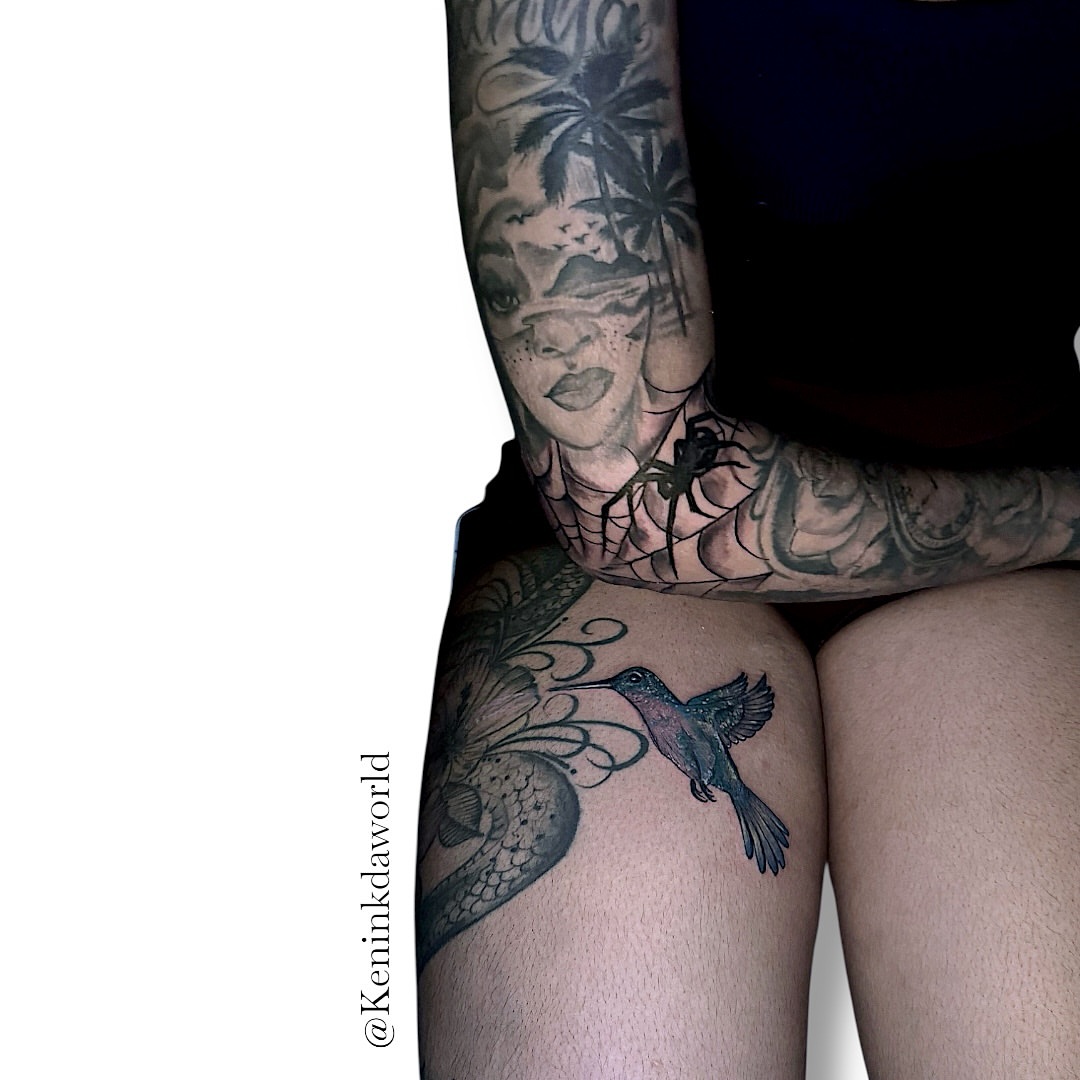 Hummingbird and flower black and grey tattoo on the thigh by Ken West