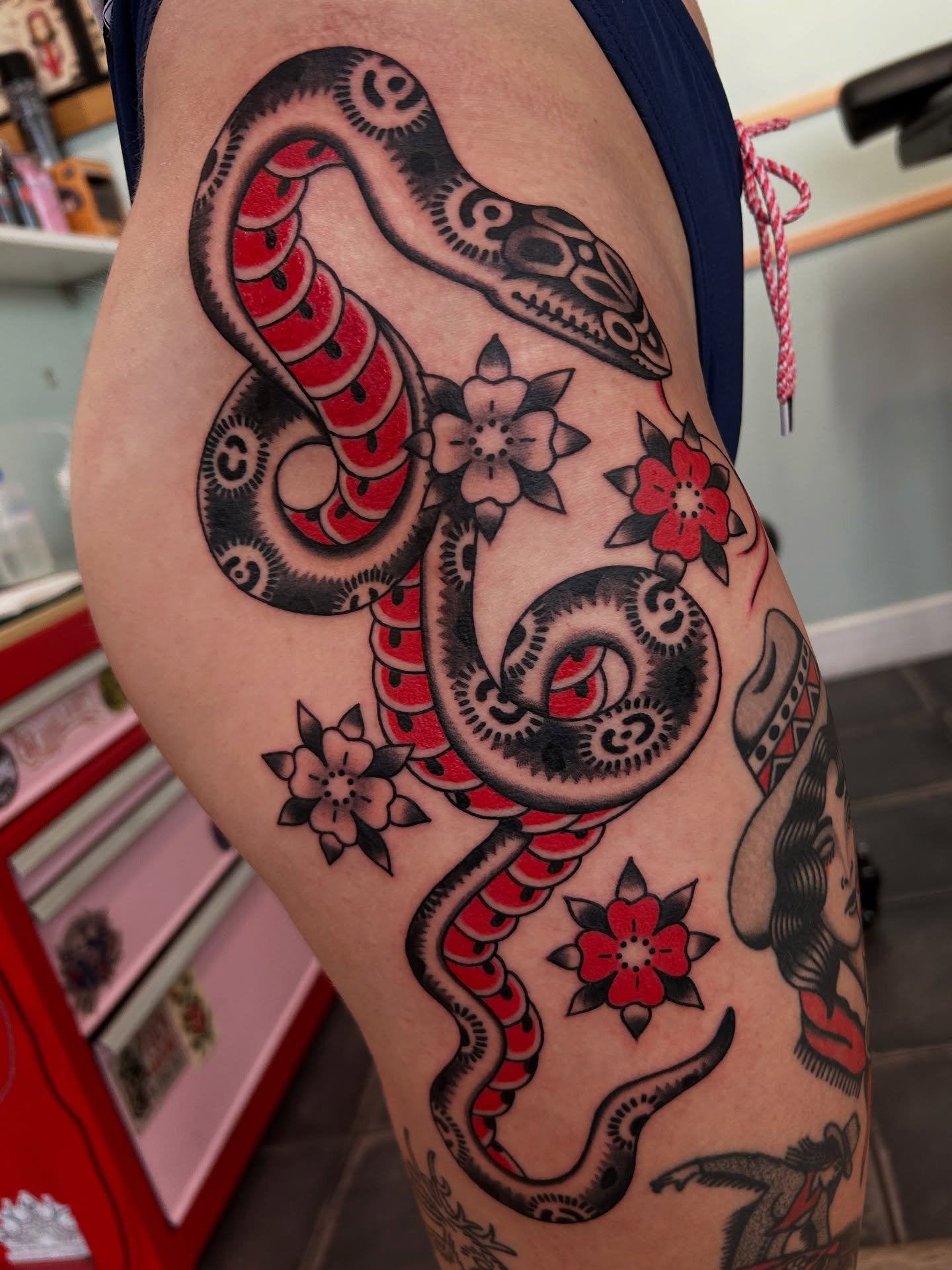 Snake and flowers American traditional tattoo on the thigh by Lilly Binns