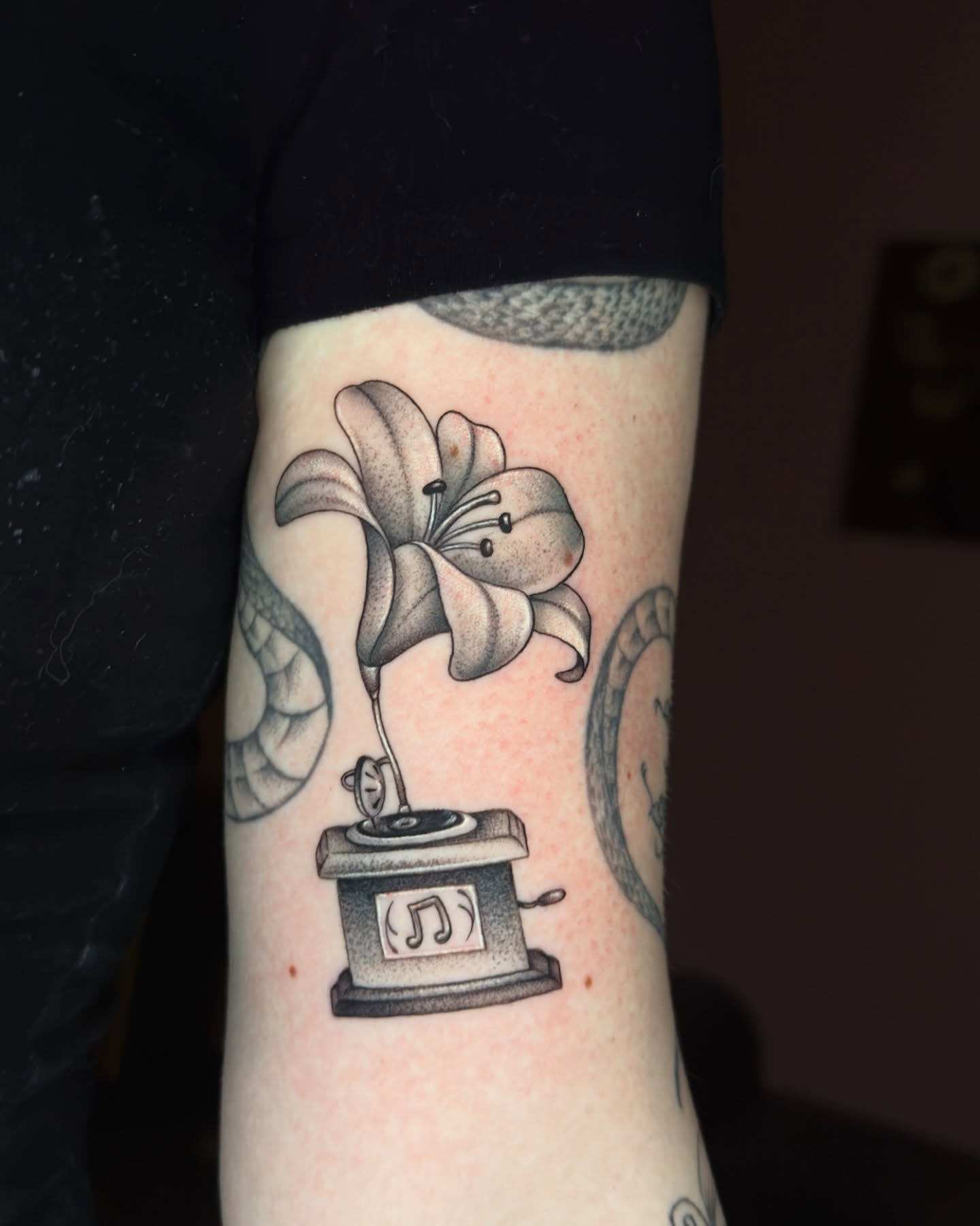 Lily and gramophone realism tattoo on the forearm by Nichole Lorence