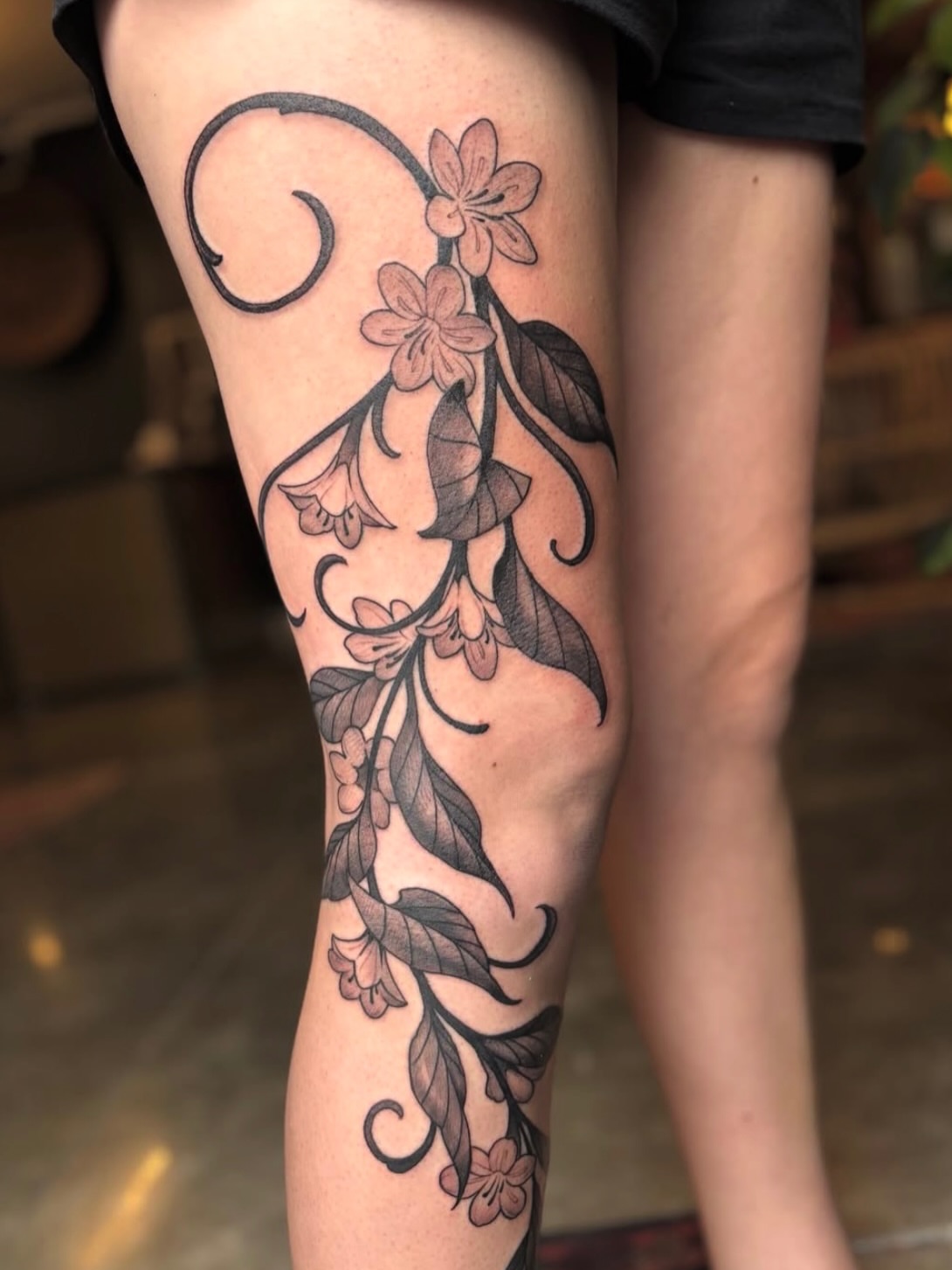 Floral vine black and grey tattoo on the thigh by Ian White