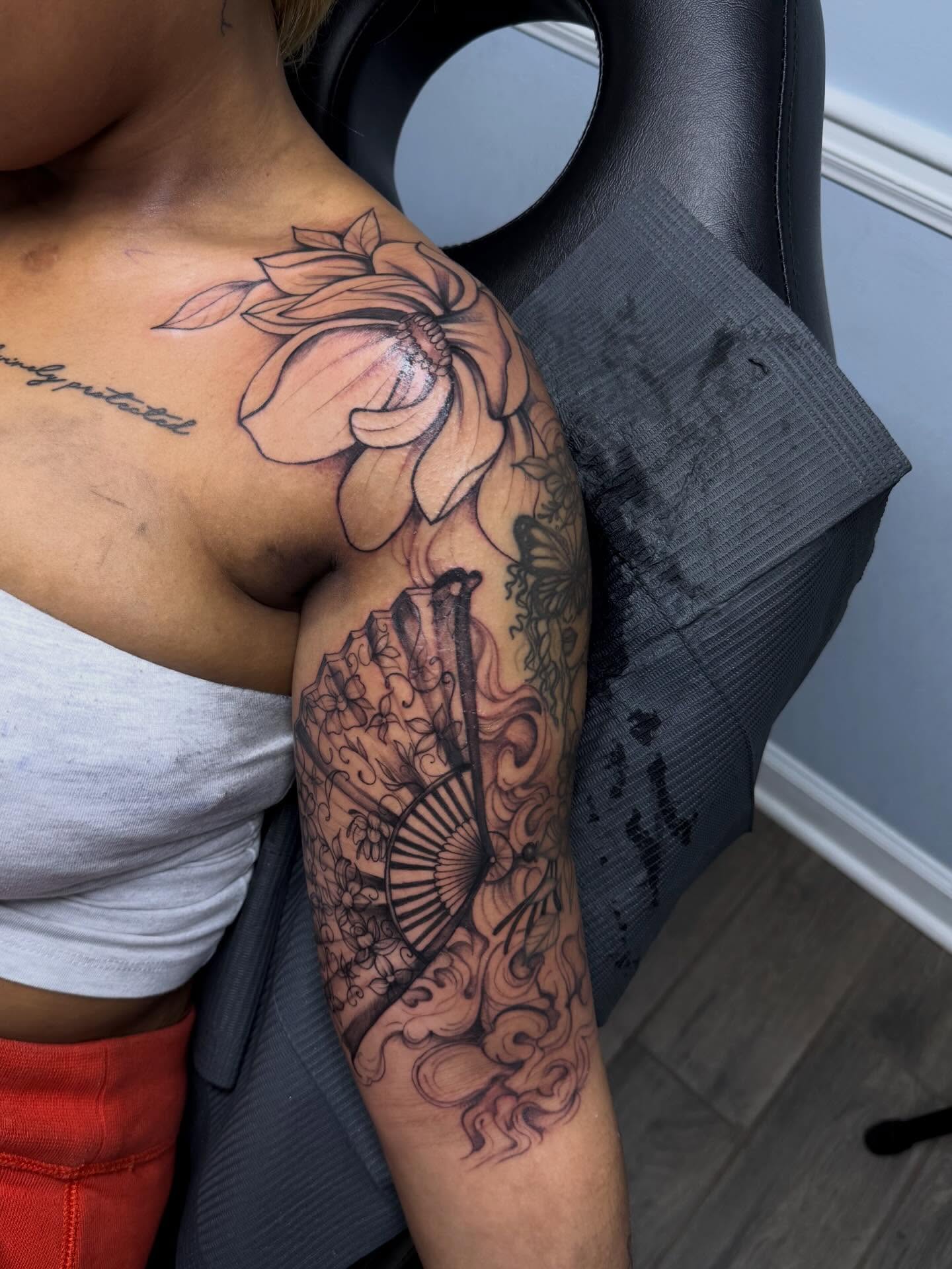 Lotus flower and fan realism tattoo on the upper arm by Stephania ATLANTA TATTOO ARTIST🎨