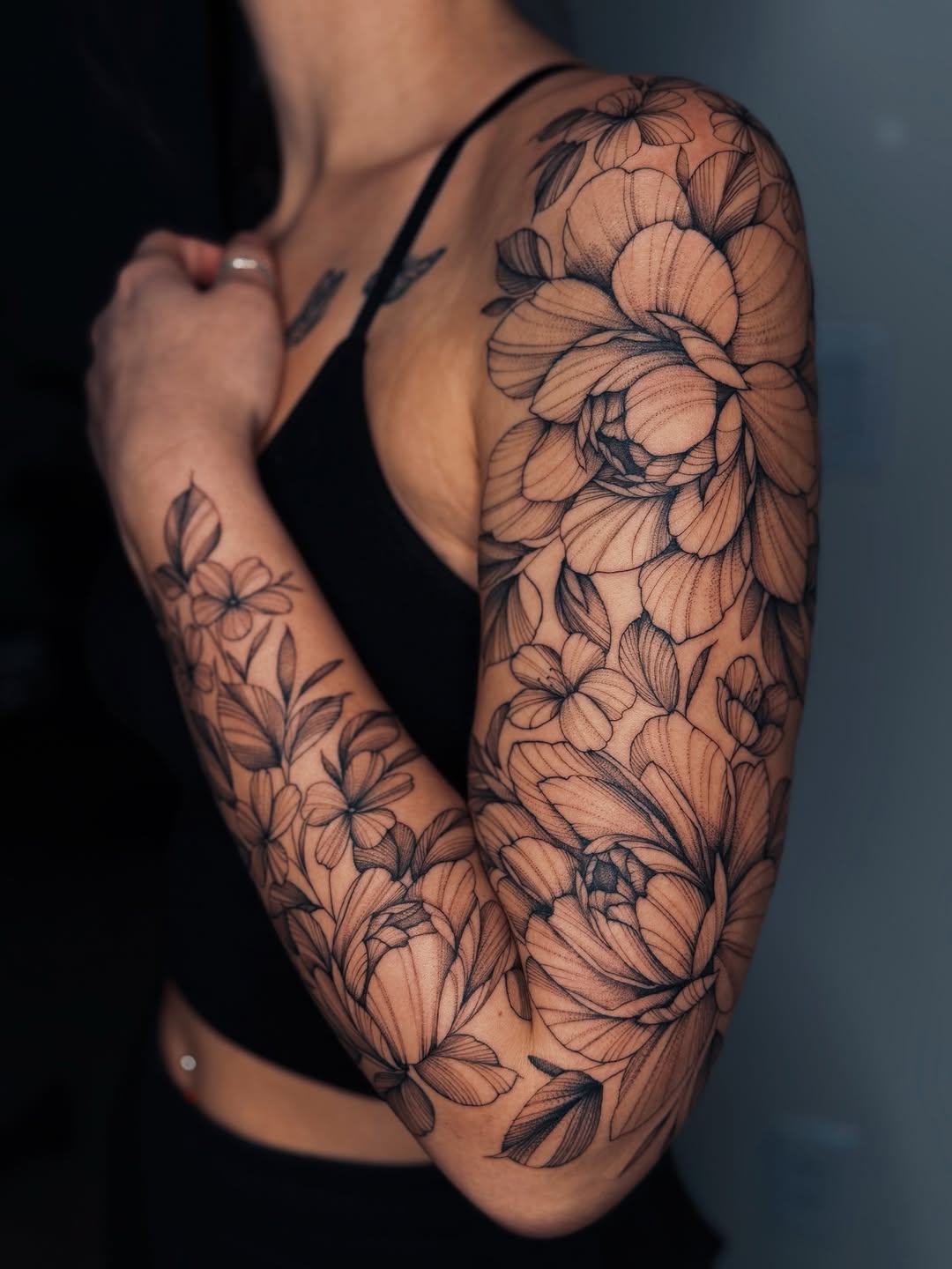 Floral sleeve fine line tattoo on the upper arm by Olha Tytarenko