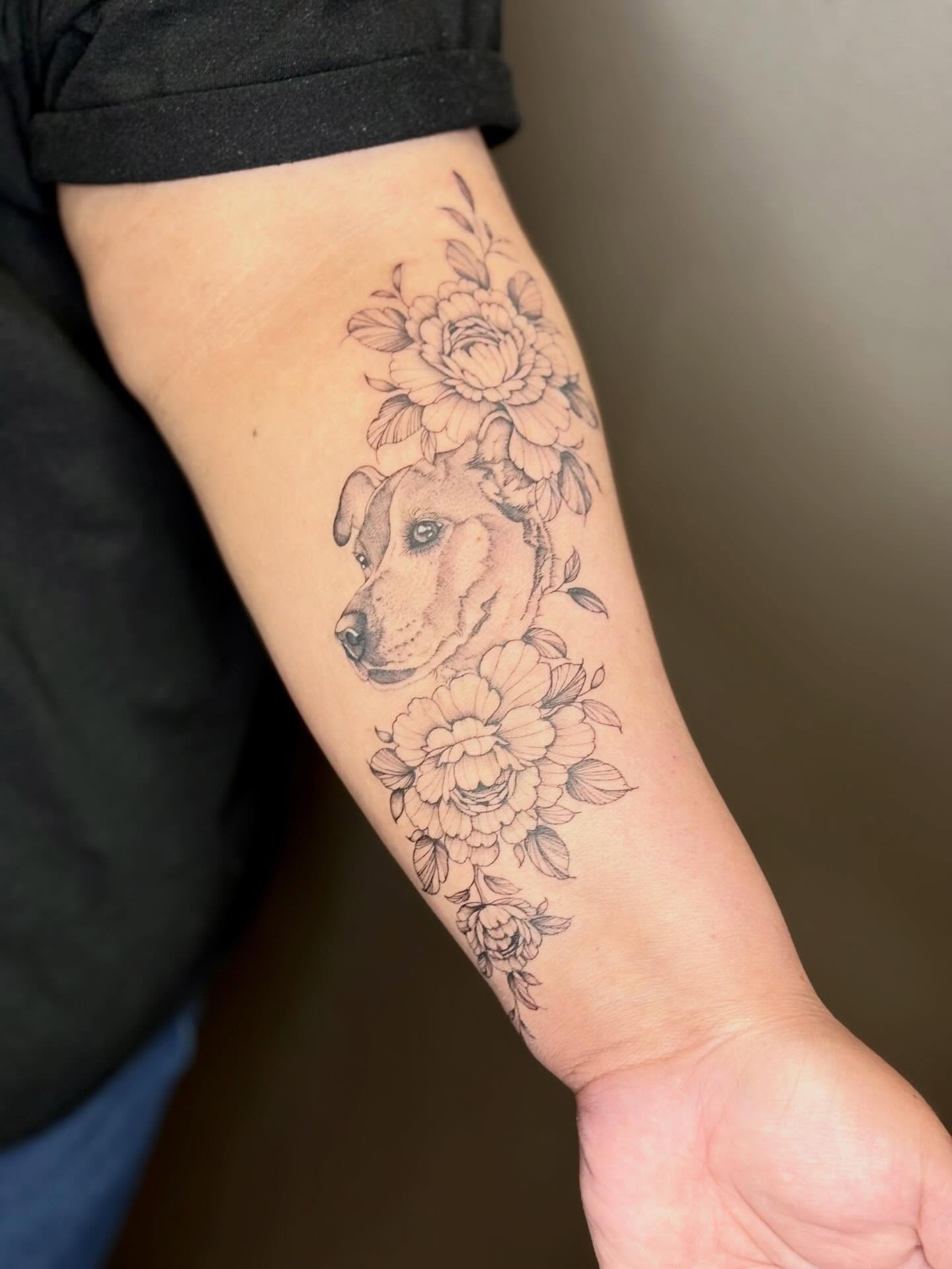 Dog with floral wreath black and grey tattoo on the forearm by 🖤Sidney🖤