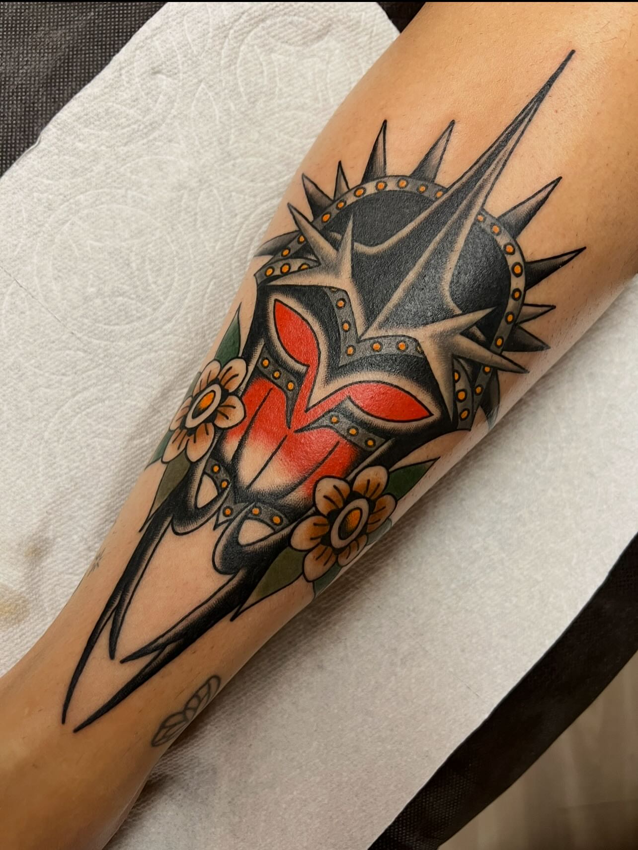 Mask with flowers American traditional tattoo on the forearm by Kelsey Lane