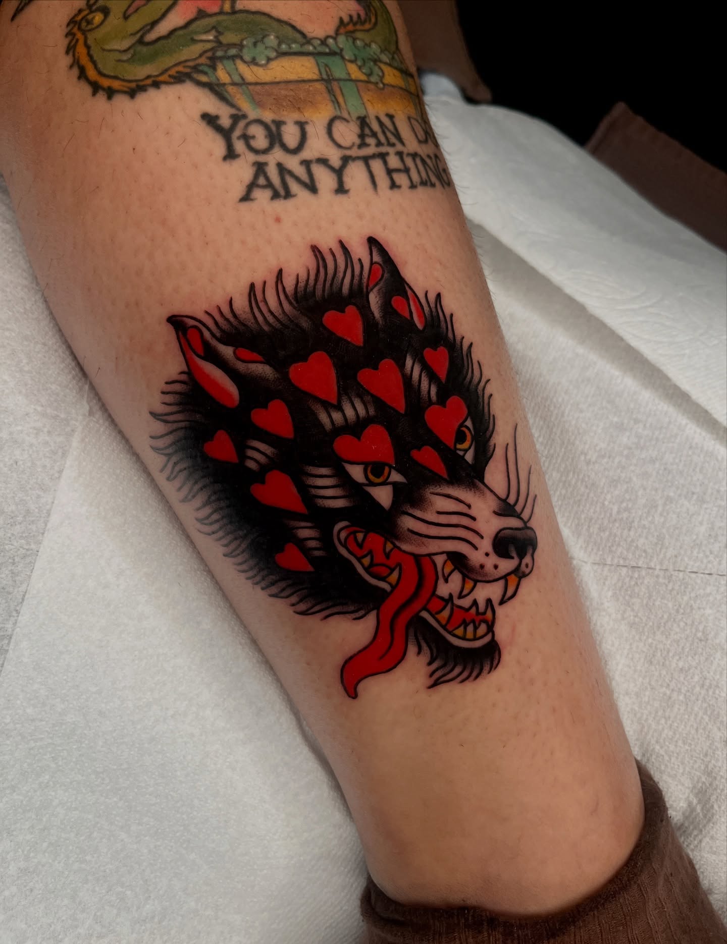Wolf with hearts American traditional tattoo on the forearm by Kehrmie Tattoos, Berkeley, California