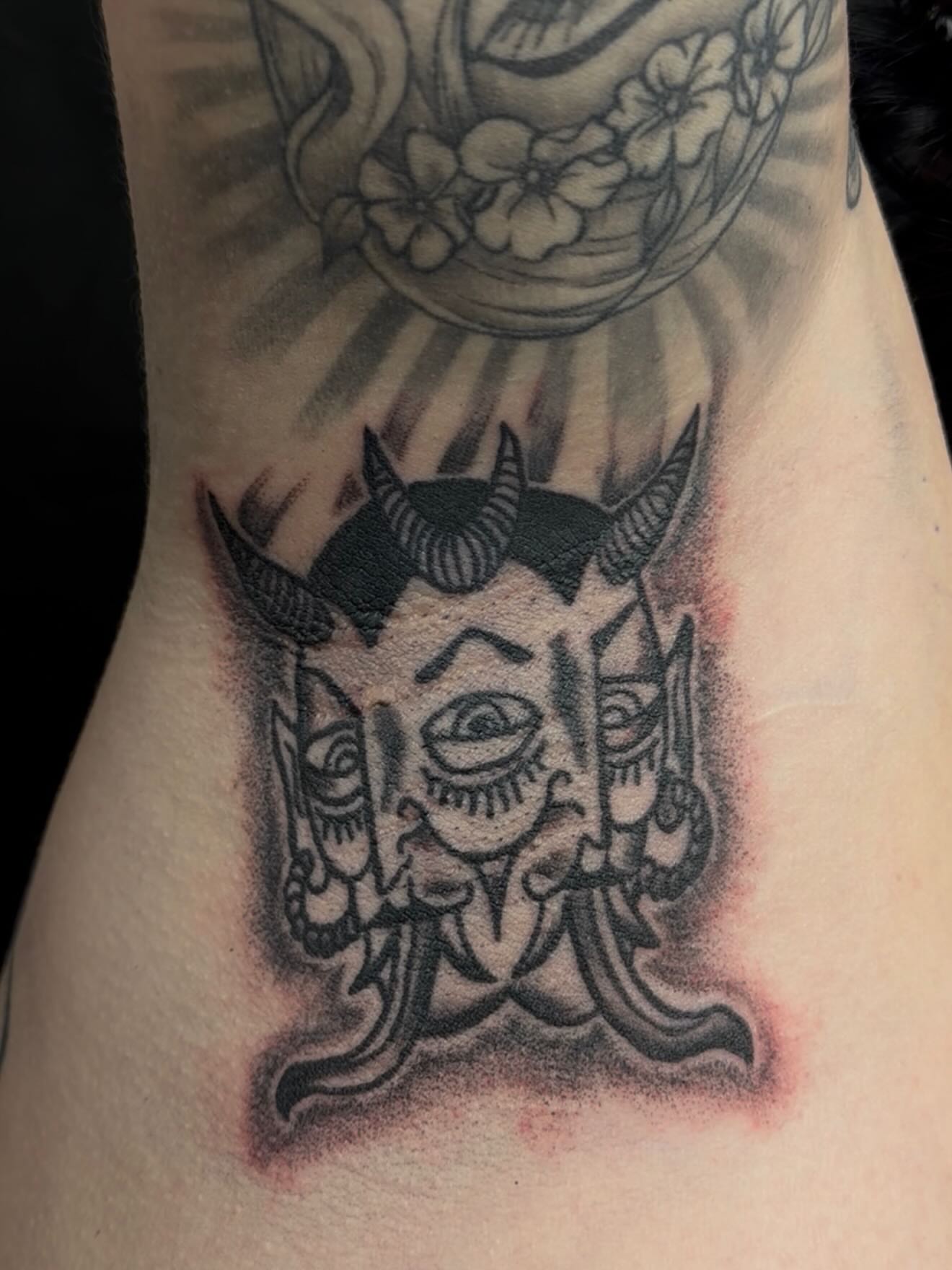 Demon mask black and grey tattoo on the thigh by cortez