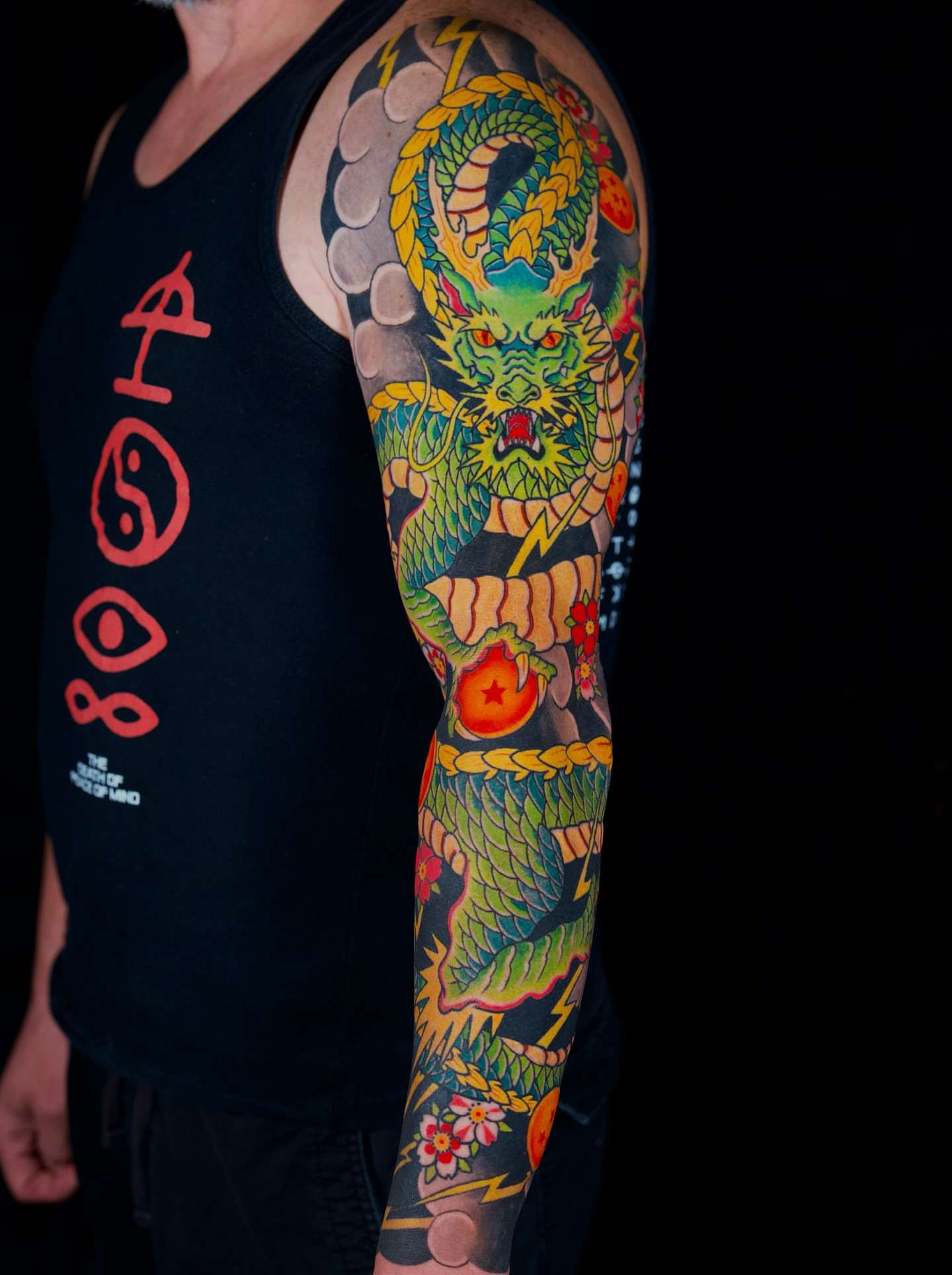 Dragon and floral American traditional tattoo on the upper arm by Mitch Bonifay