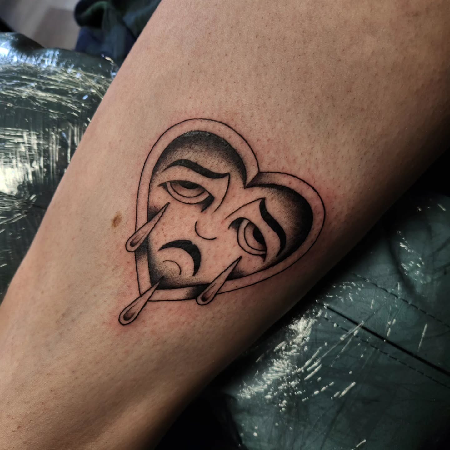 Tearful face black and grey tattoo on the forearm by Gavvo
