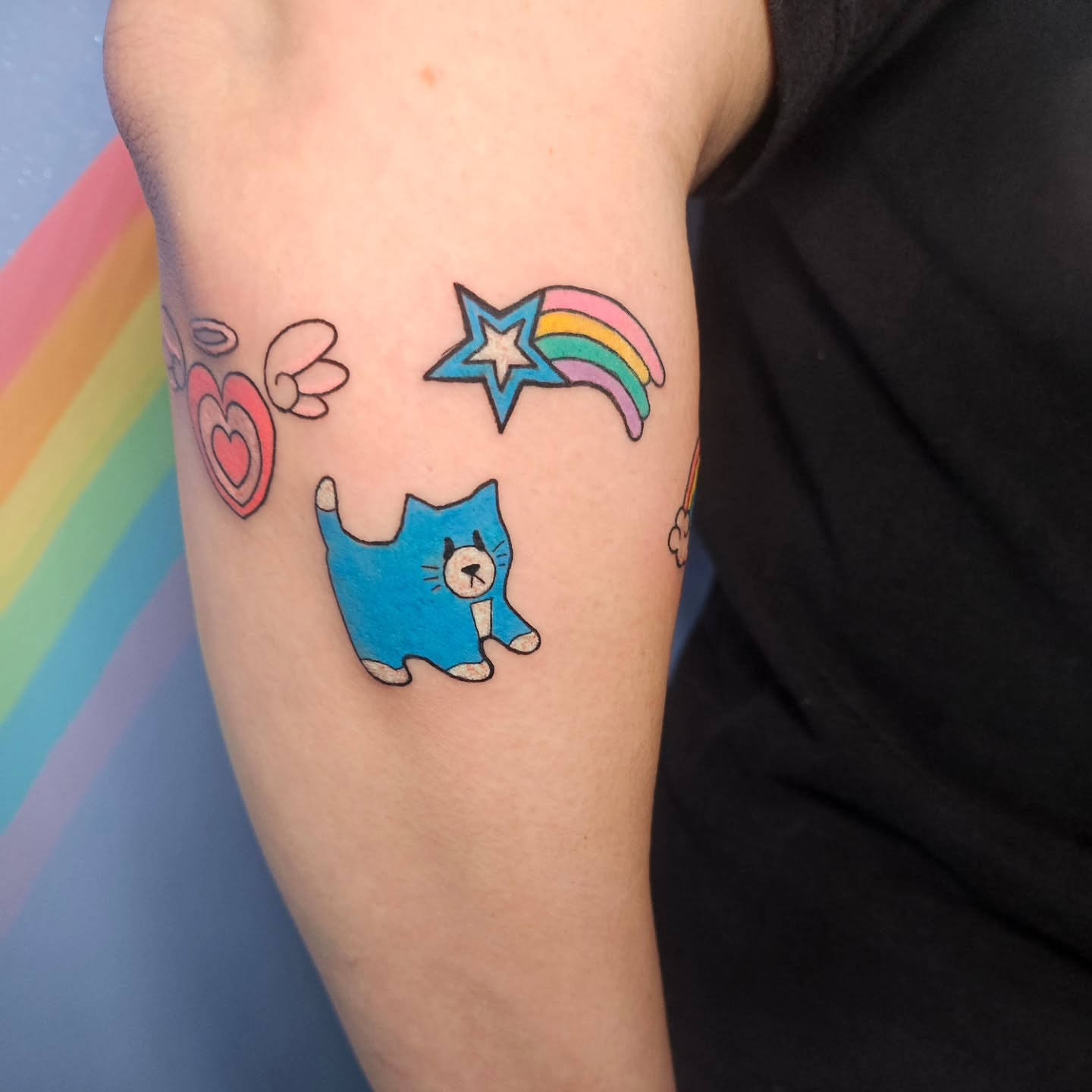 Cat and rainbow new school tattoo on the forearm by Gray