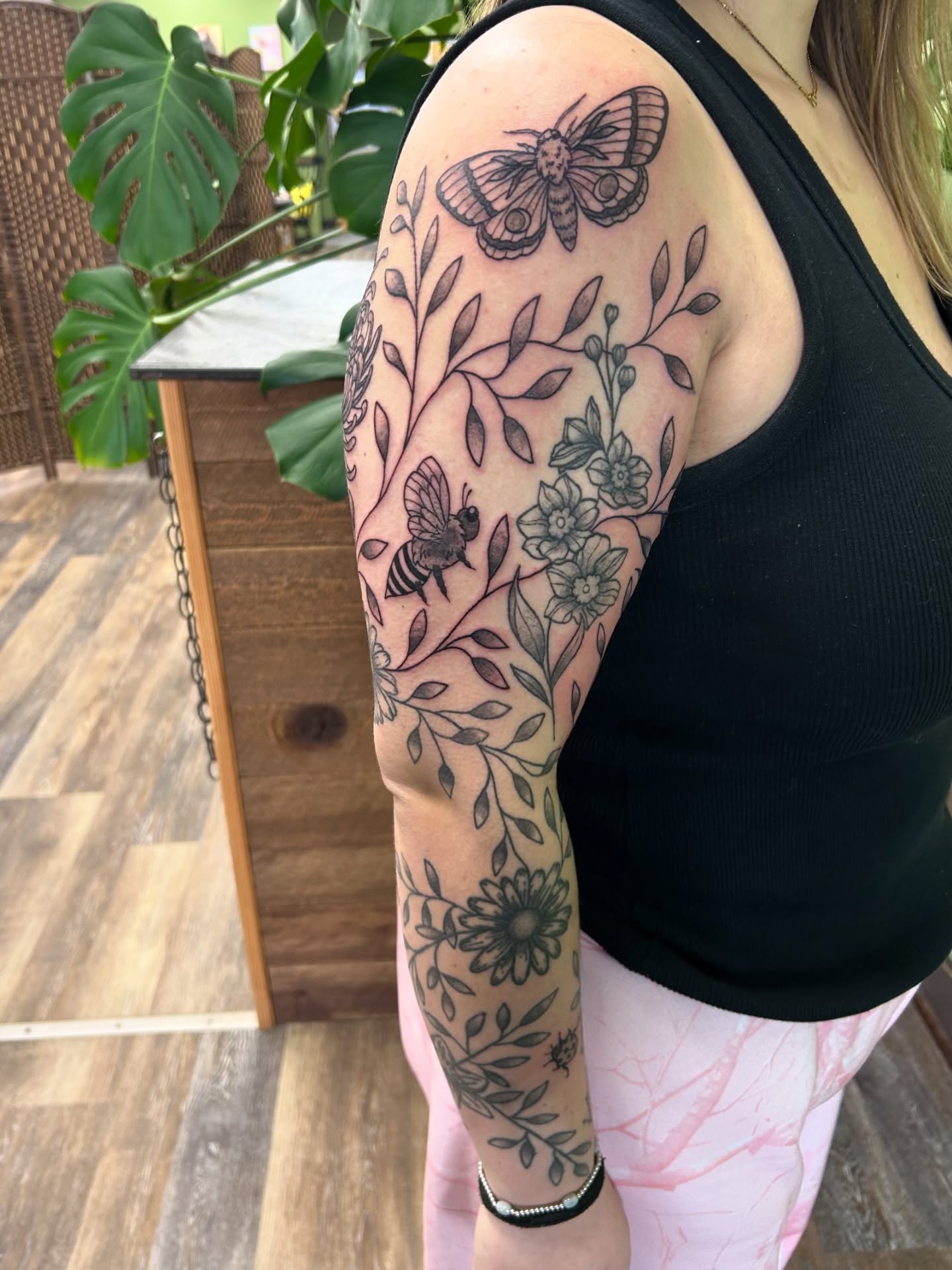 Botanical and insect black and grey tattoo on the upper arm by Courtney
