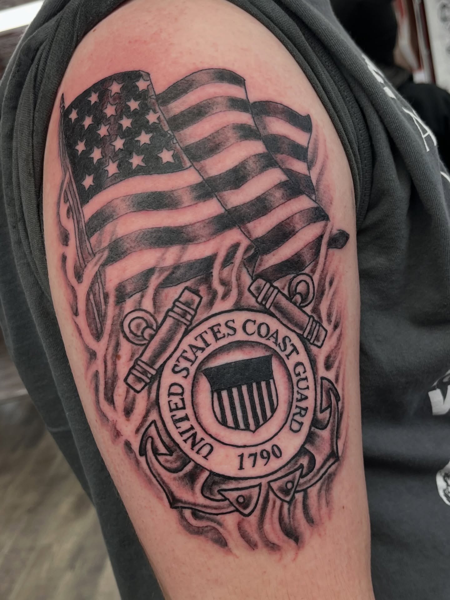 United States Coast Guard emblem black and grey tattoo on the shoulder by Steve Tiberi