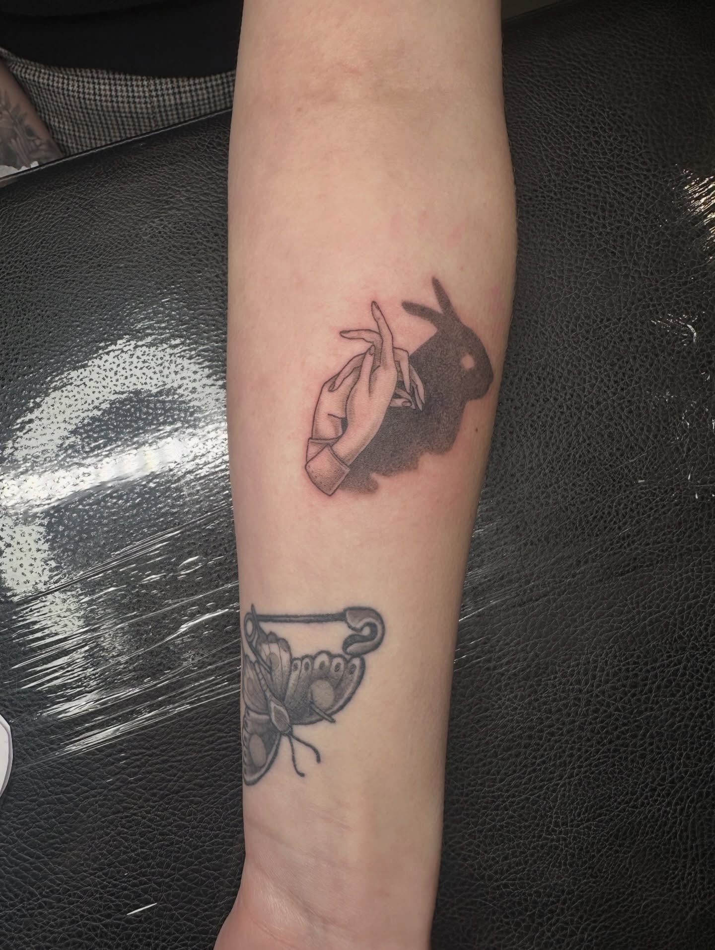 Rabbit and hand black and grey tattoo on the forearm by Emma Thompson
