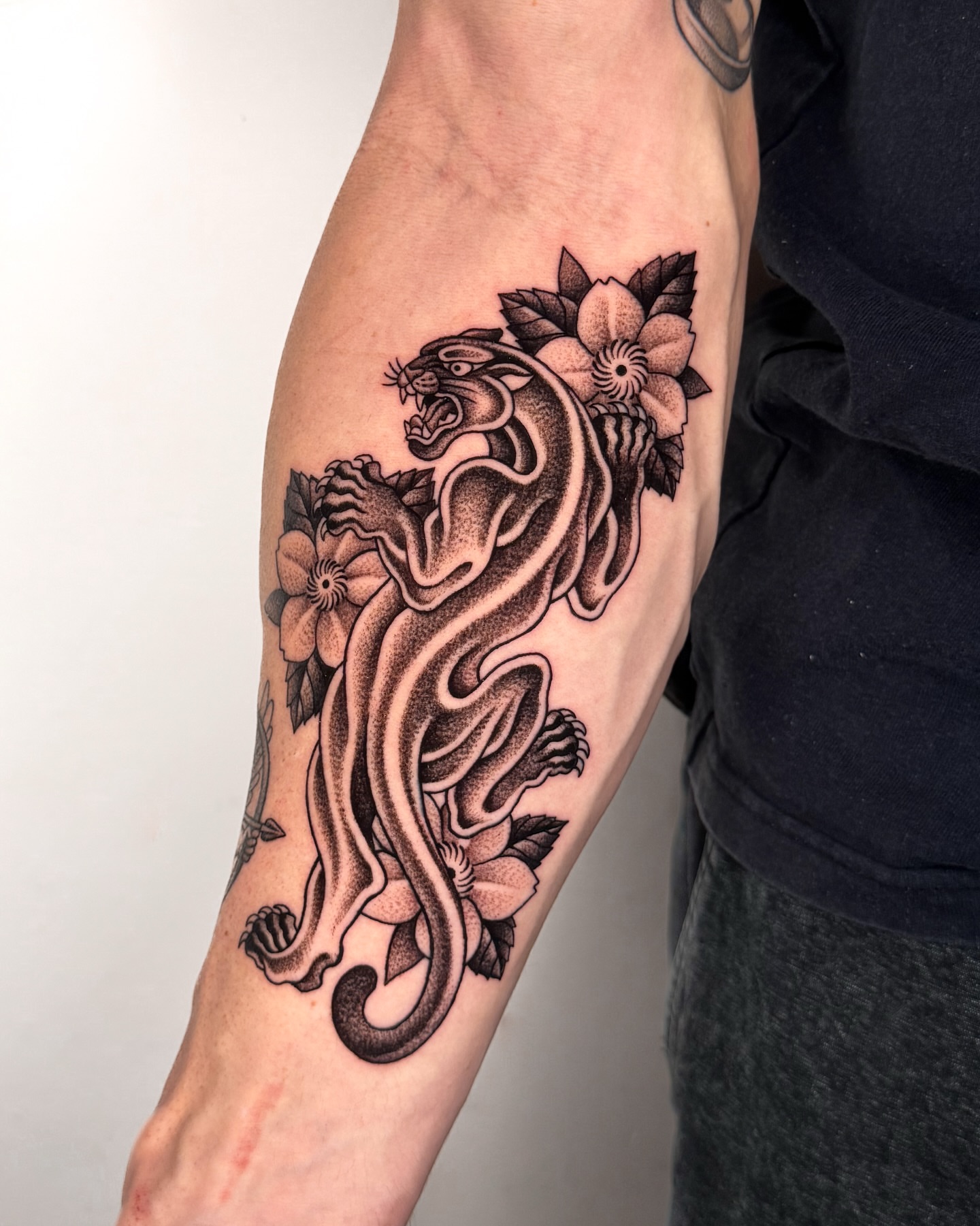 Panther and flowers black and grey tattoo on the forearm by Jae Traditional Tattoo