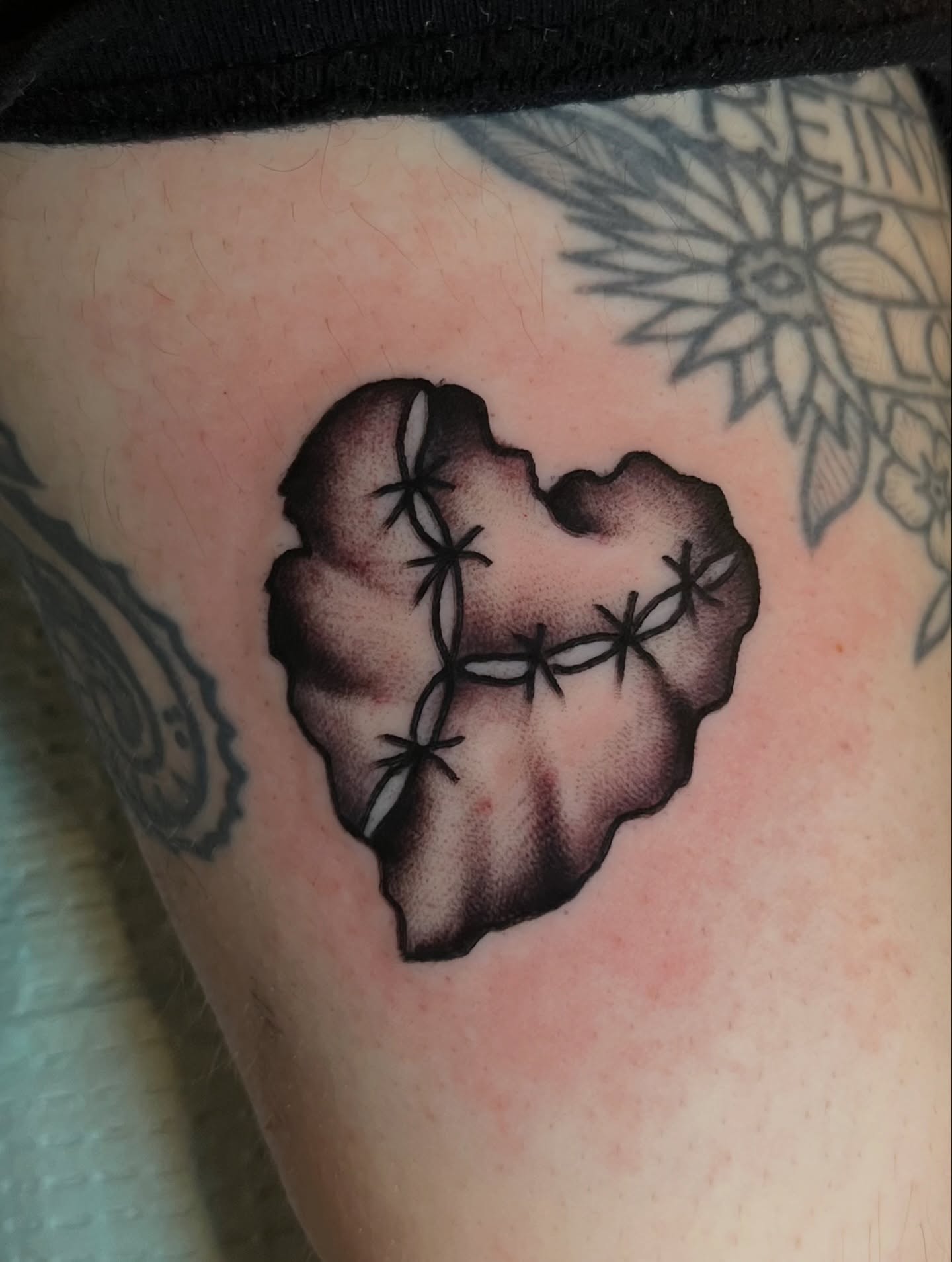 Heart with barbed wire black and grey tattoo on the thigh by Anthony Tattooer, Seattle, Washington