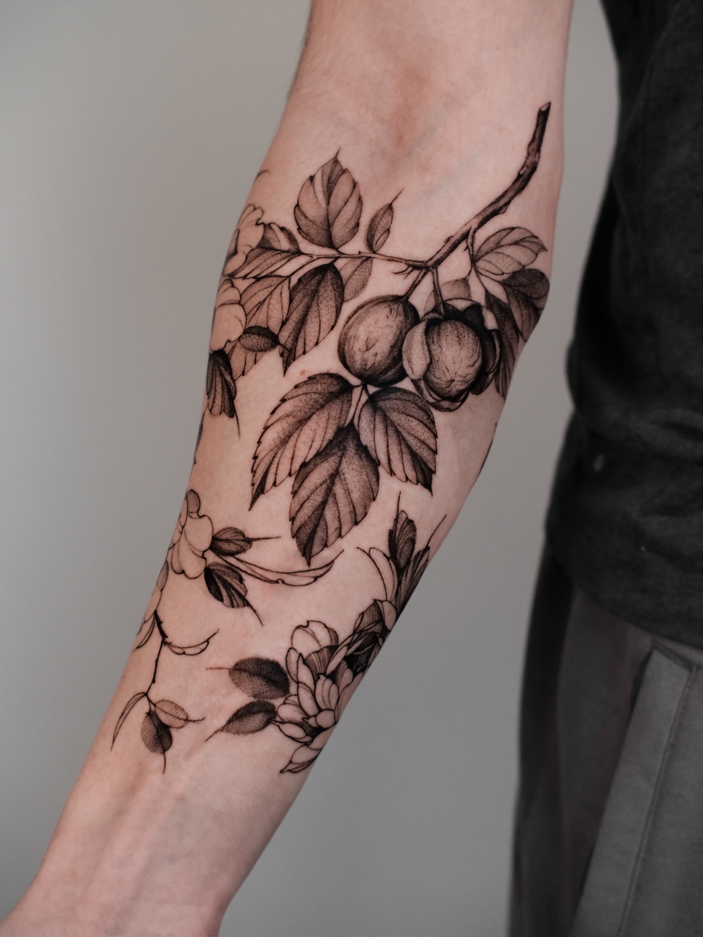 Branch with fruits and flowers realism tattoo on the forearm by Anastasiia