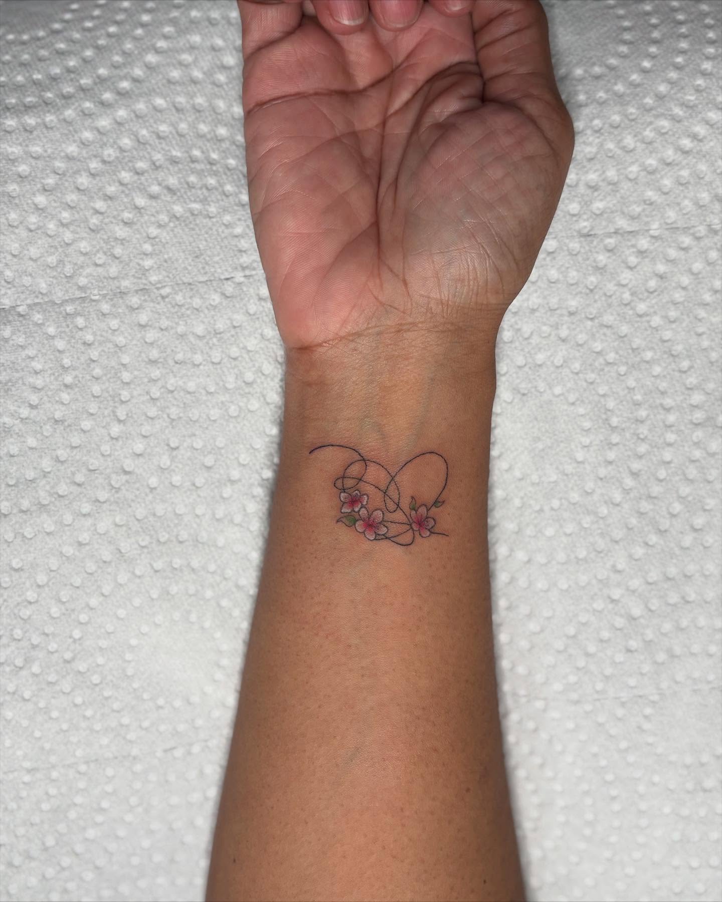 Cherry blossoms fine line tattoo on the forearm by Tessa Simmons - Tattoo Artist
