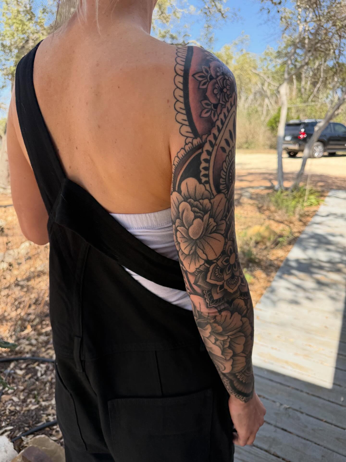 Floral black and grey tattoo on the upper arm by Rebecca Basma Smith