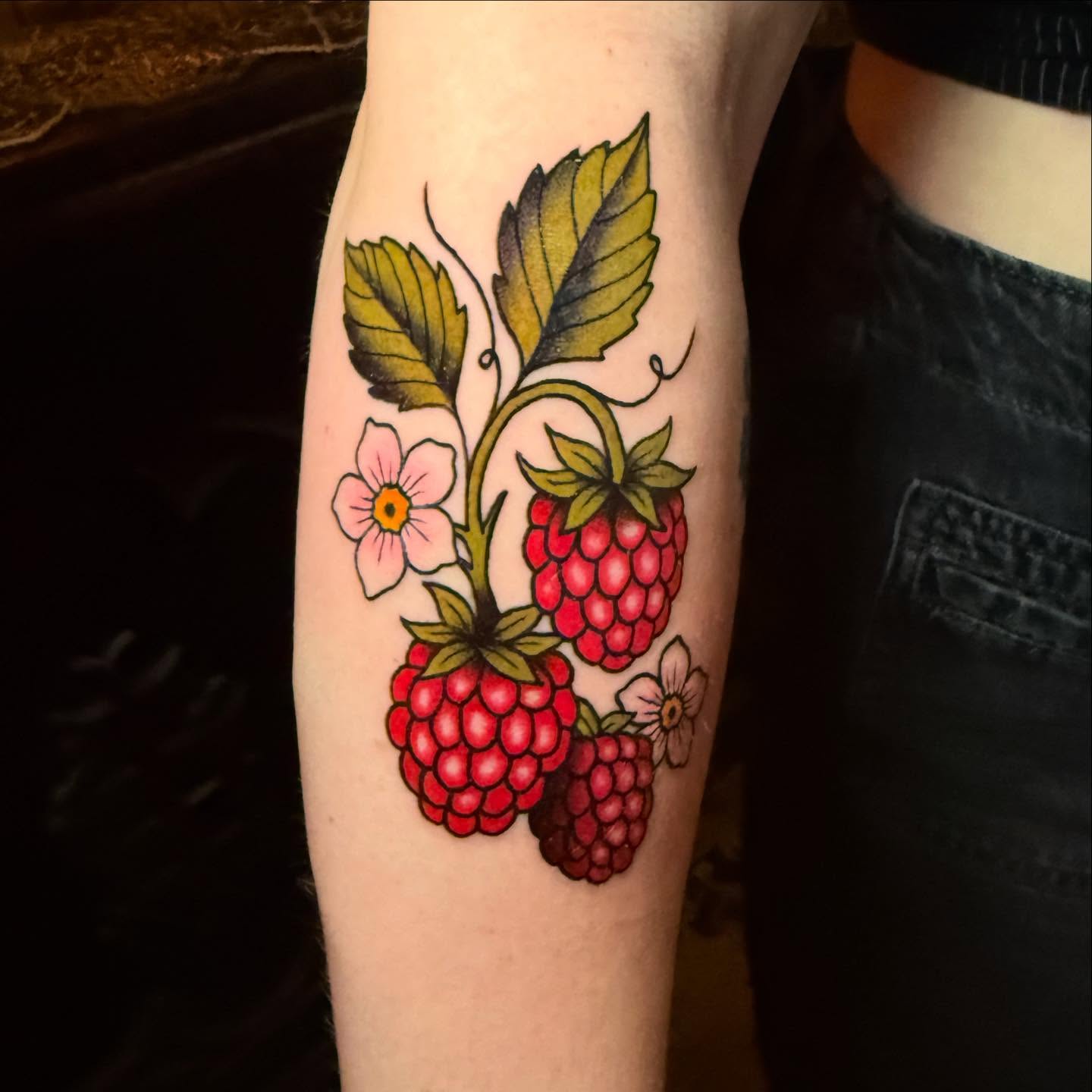 Raspberries and flowers American traditional tattoo on the forearm by Emily Lestrange