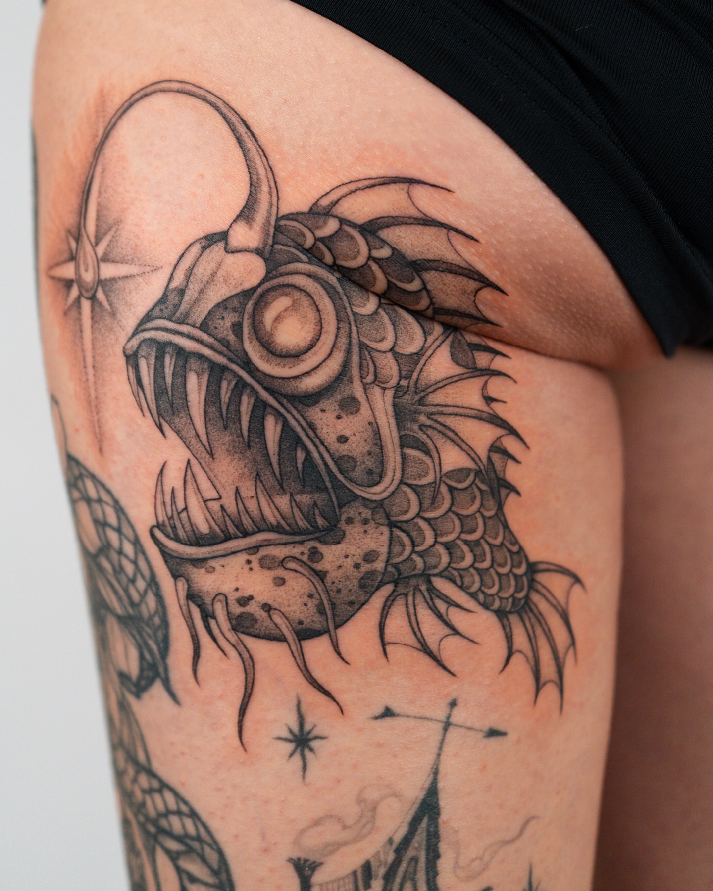 Angler fish black and grey tattoo on the thigh by Mikayla Sue