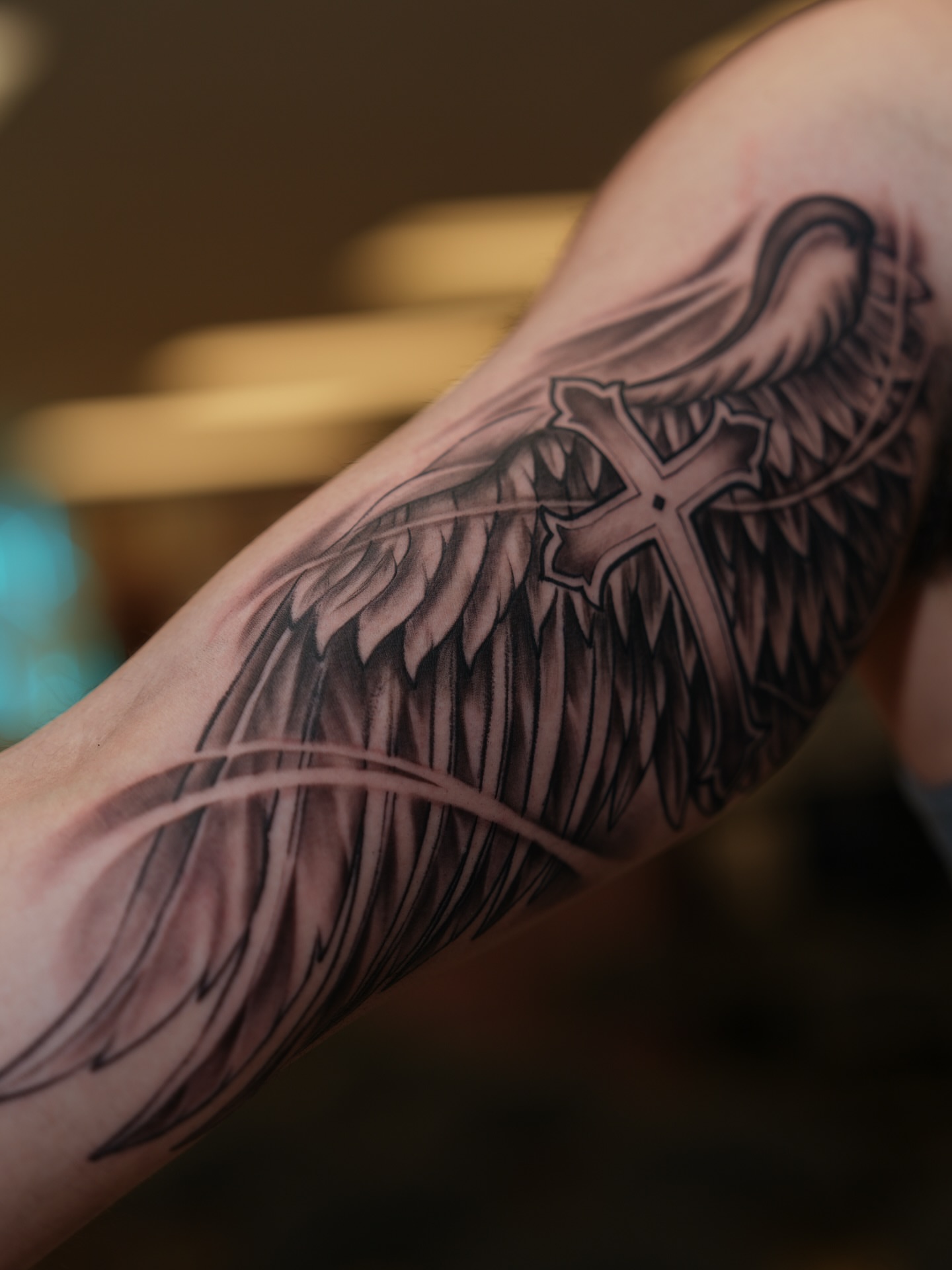 Wings and cross black and grey tattoo on the forearm by Kevin Betancourt