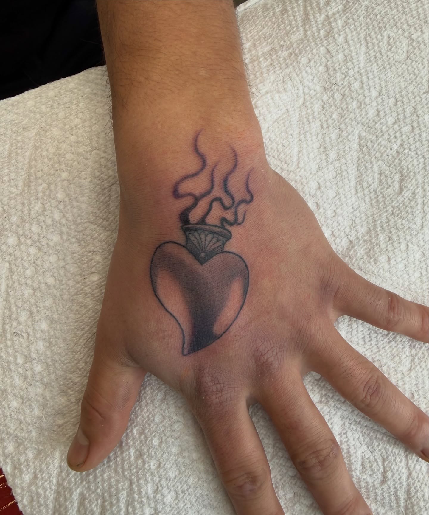 Burning heart black and grey tattoo on the hand by Ricky Sanchez, Duncanville, Texas