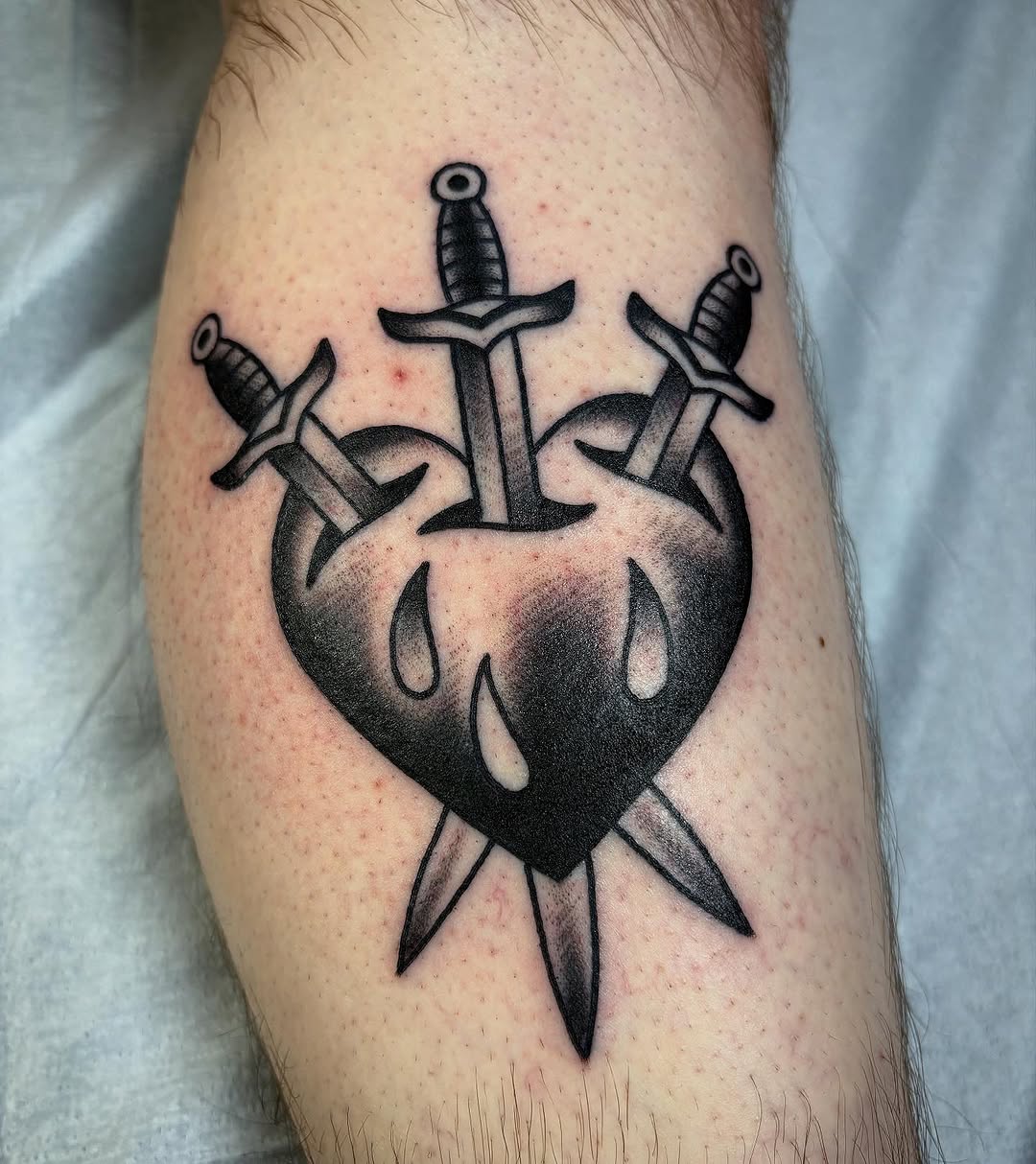Heart with three swords American traditional tattoo on the forearm by Tom Wenzell