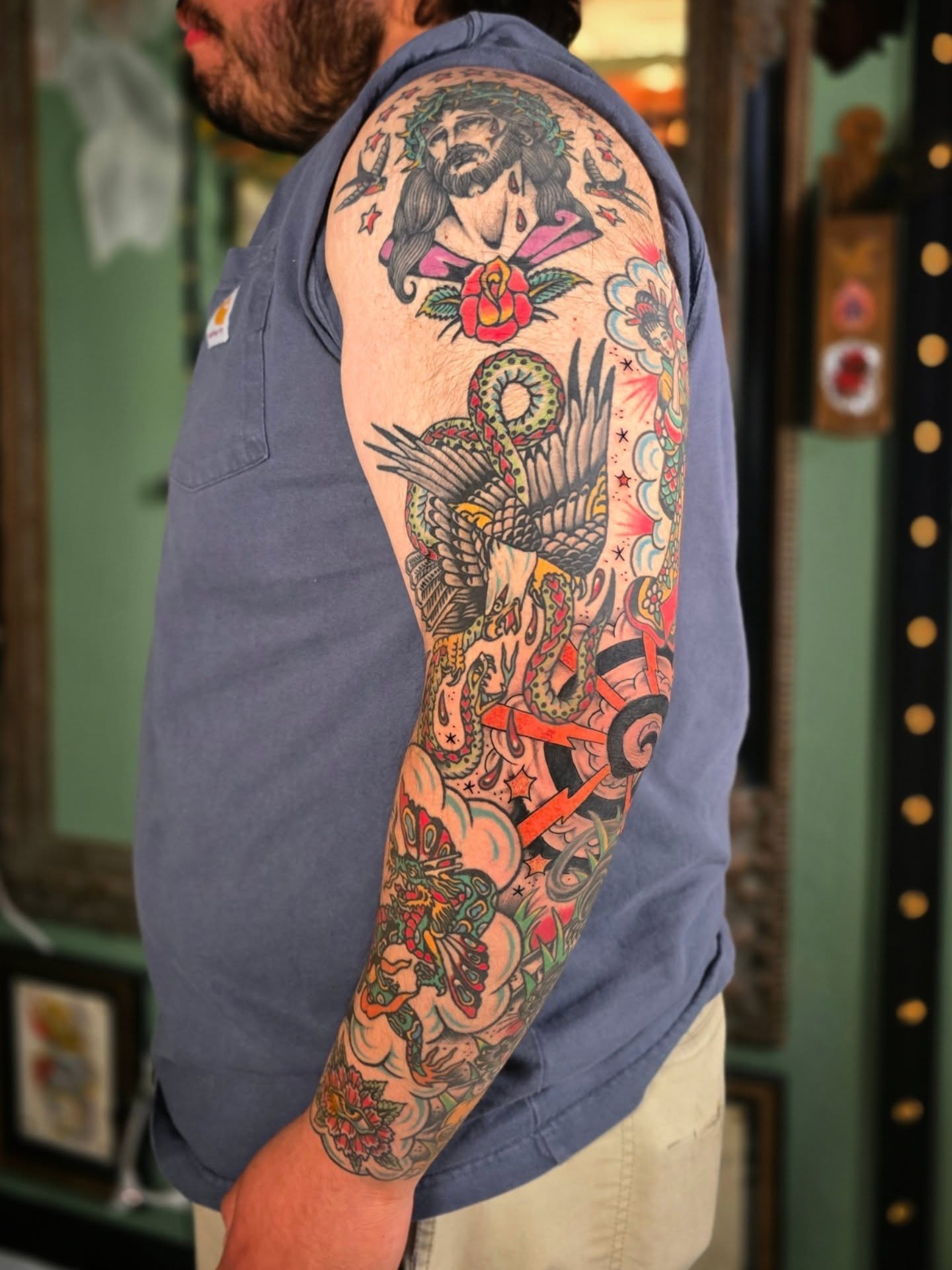 Religious figure with snake American traditional tattoo on the upper arm by Aaron Dor