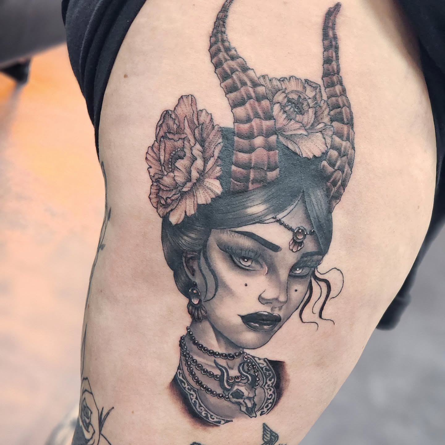 Woman with horns and flowers realism tattoo on the thigh by Robert Glover