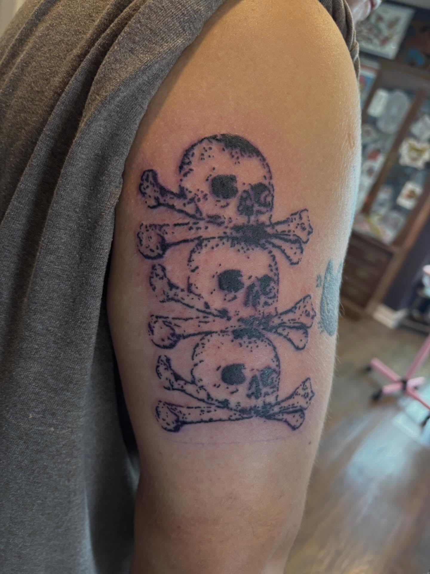 Skulls and crossbones dotwork tattoo on the shoulder by Turner