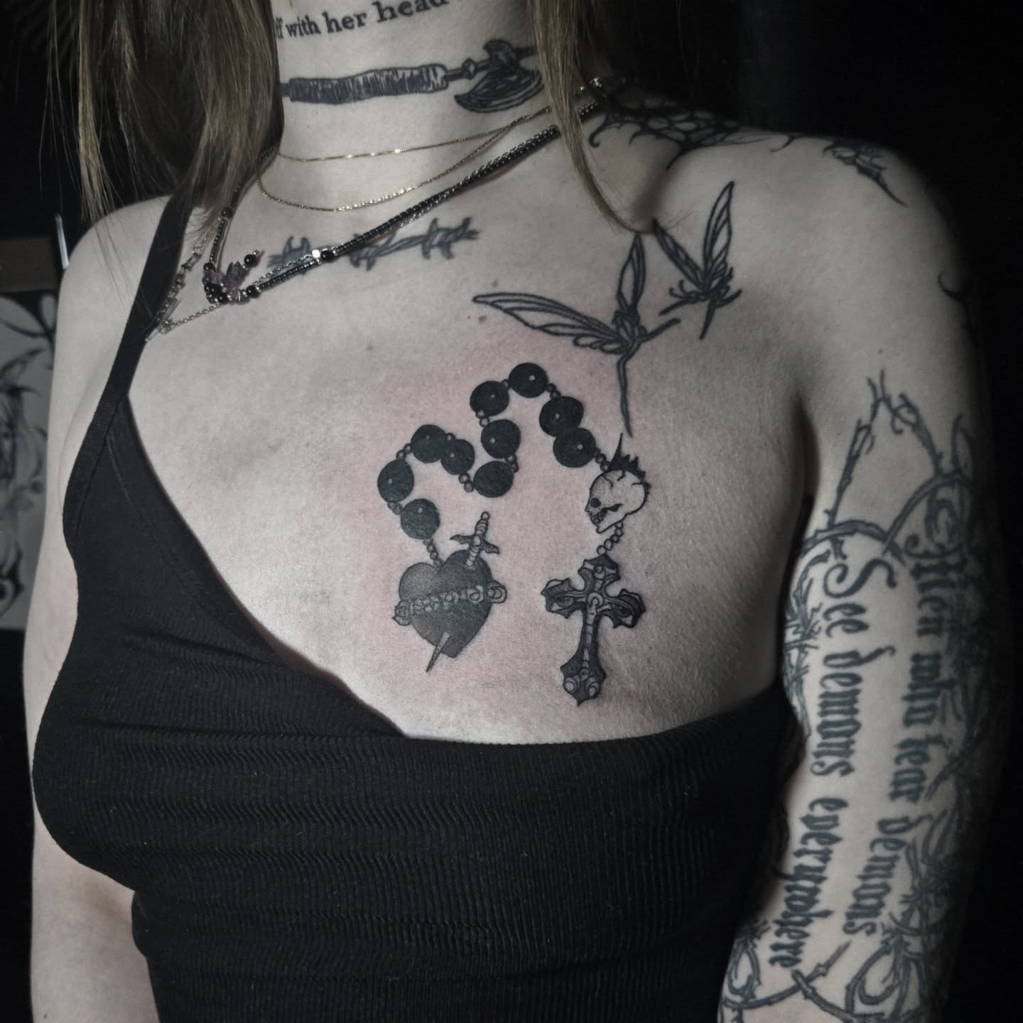 Rosary and cross black and grey tattoo on the chest by Ema Fish