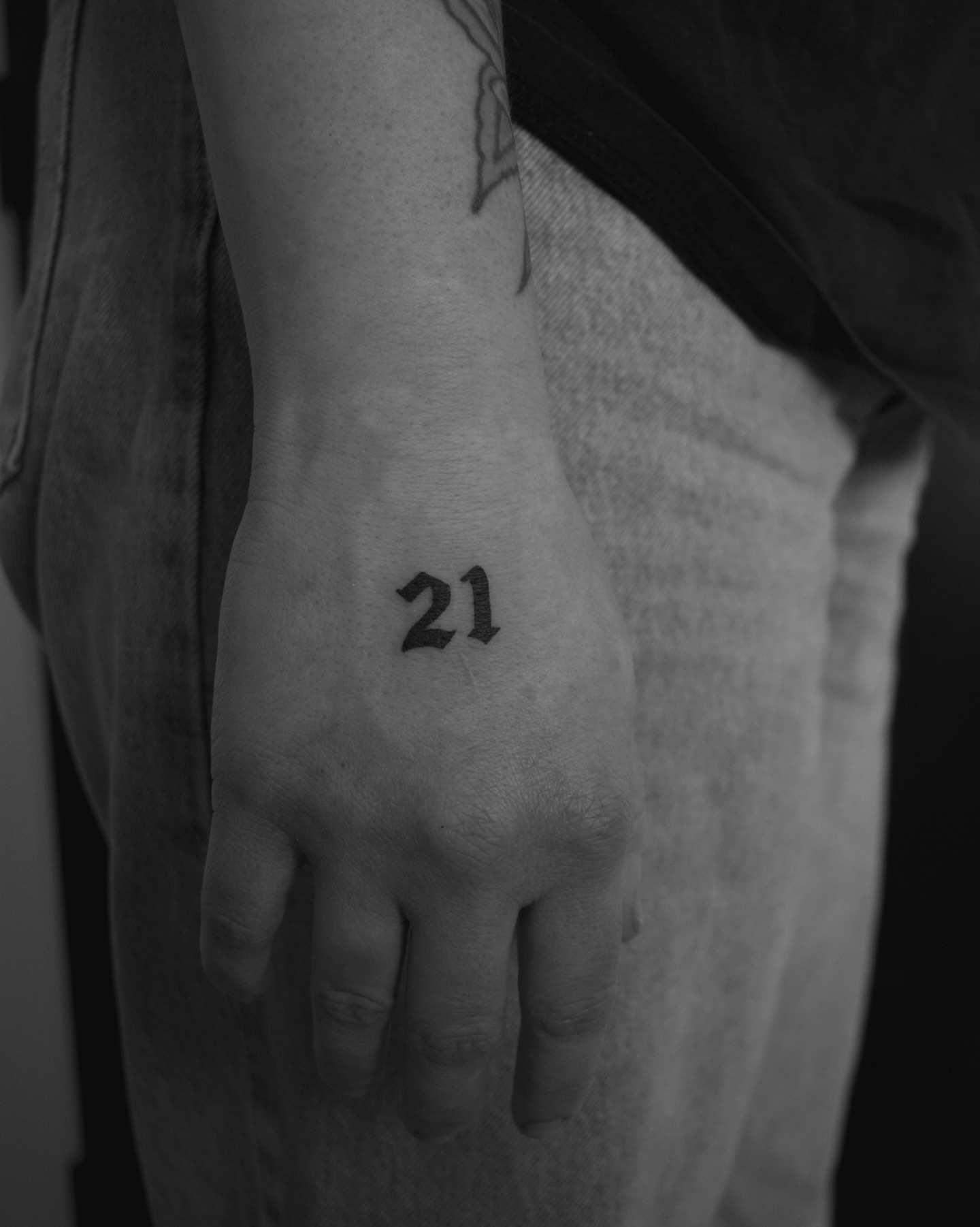 Number 21 black and grey tattoo on the hand by Haley Sayers