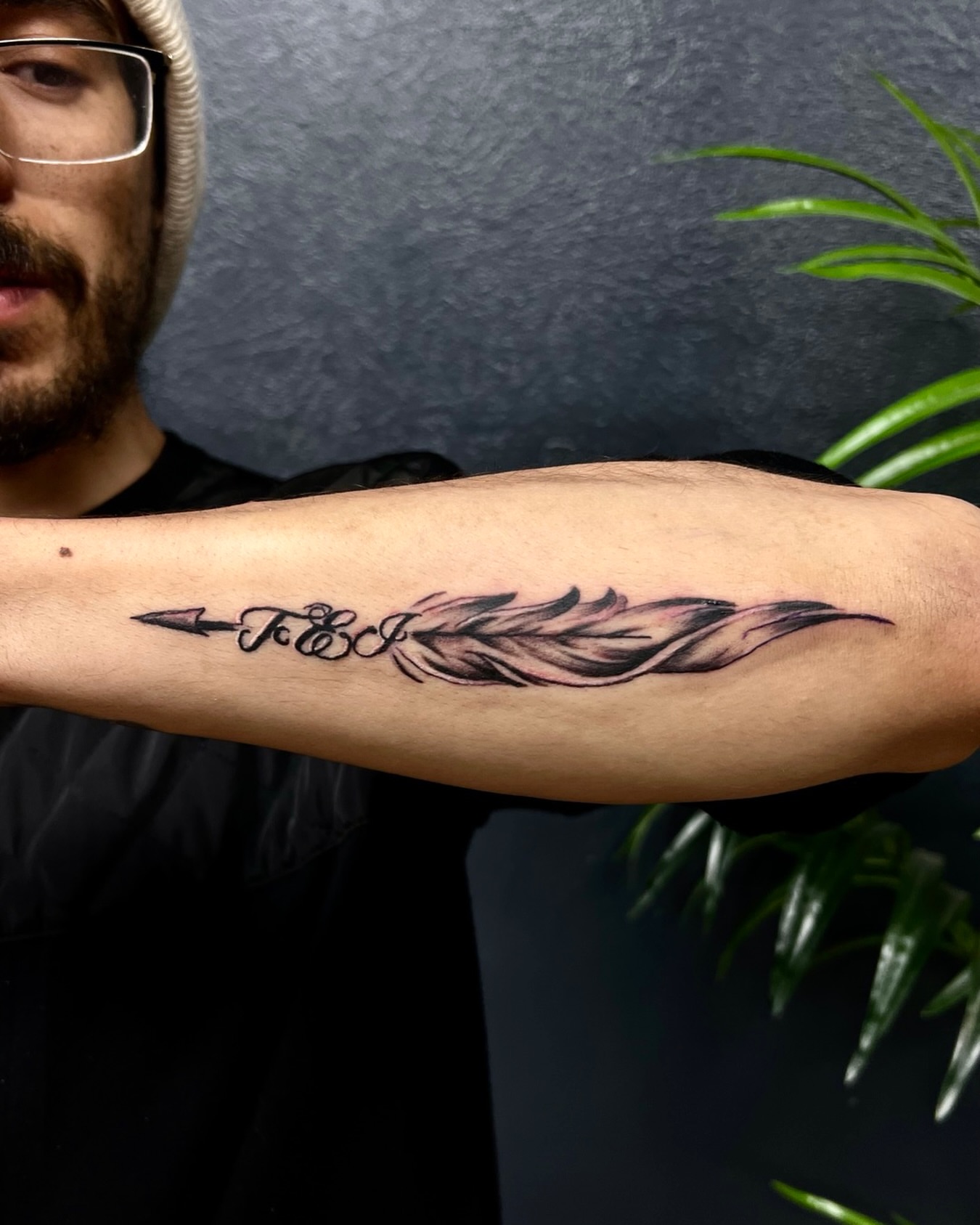 Feather and arrow black and grey tattoo on the forearm by Deacon Moser
