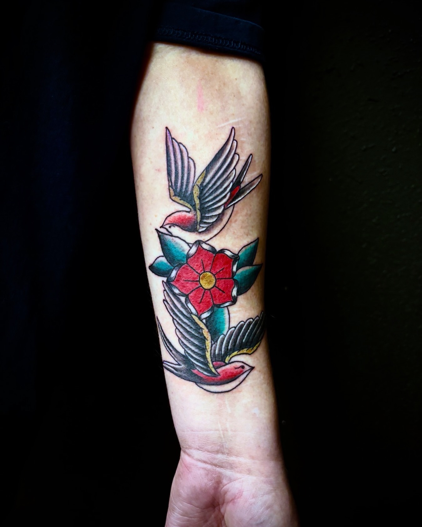 Bird and flower American traditional tattoo on the forearm by Deacon Moser