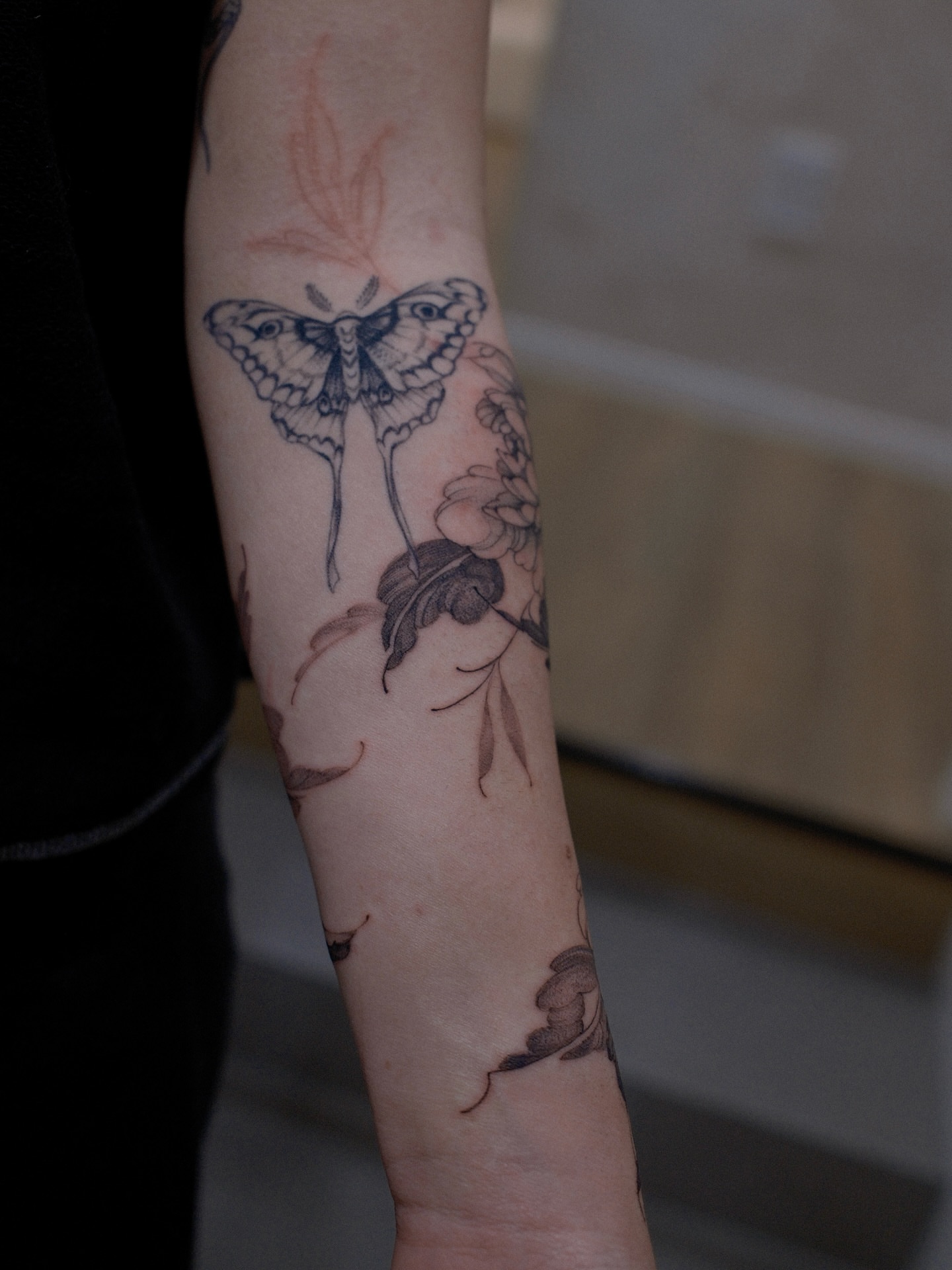 Moth and flowers black and grey tattoo on the forearm by Joy, Gold Coast, Queensland