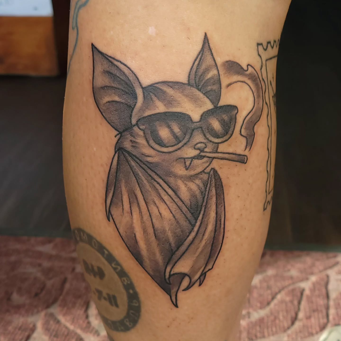 Bat wearing sunglasses black and grey tattoo on the forearm by Austin Berry