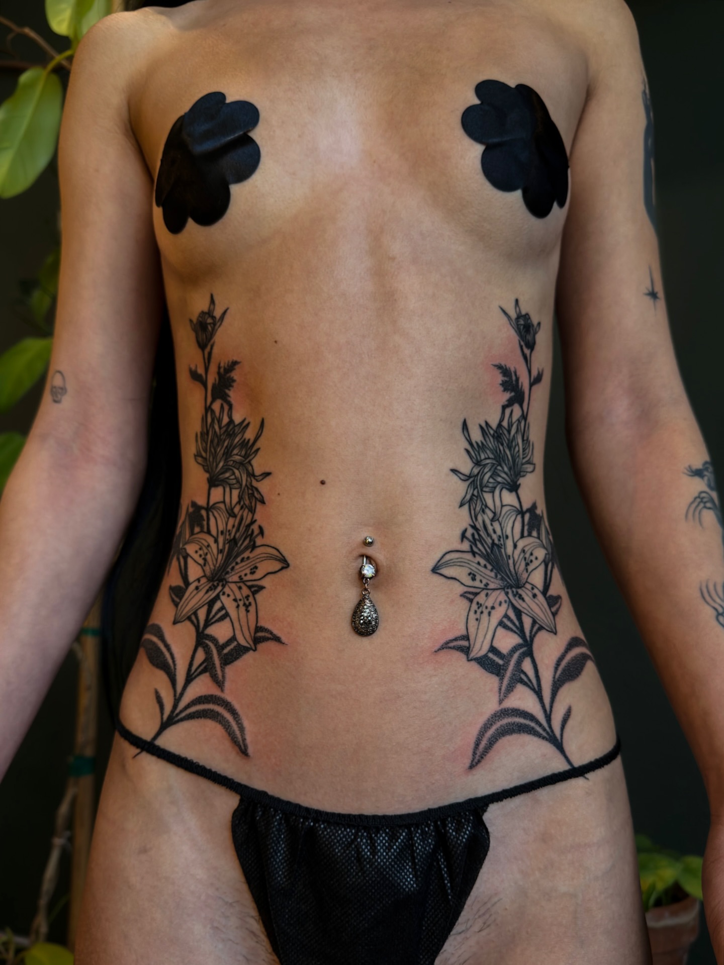 Lilies black and grey tattoo on the torso by Alexandra Gray