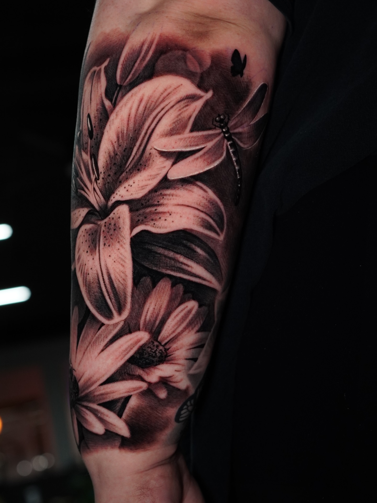 Lily and daisy realism tattoo on the forearm by Jesse Missman