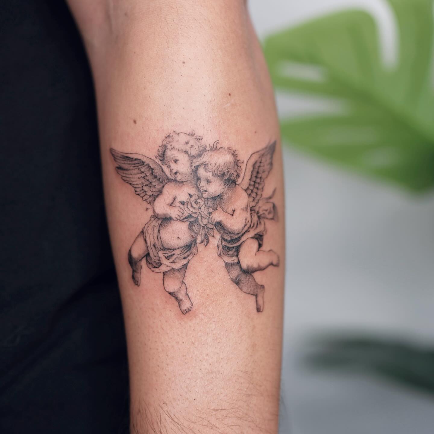 Cherubs black and grey tattoo on the forearm by Nina