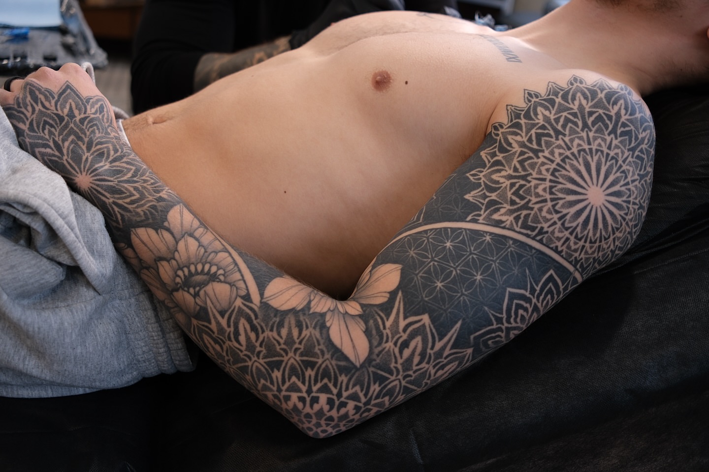 Mandala black and grey tattoo on the upper arm by Laure Conzales