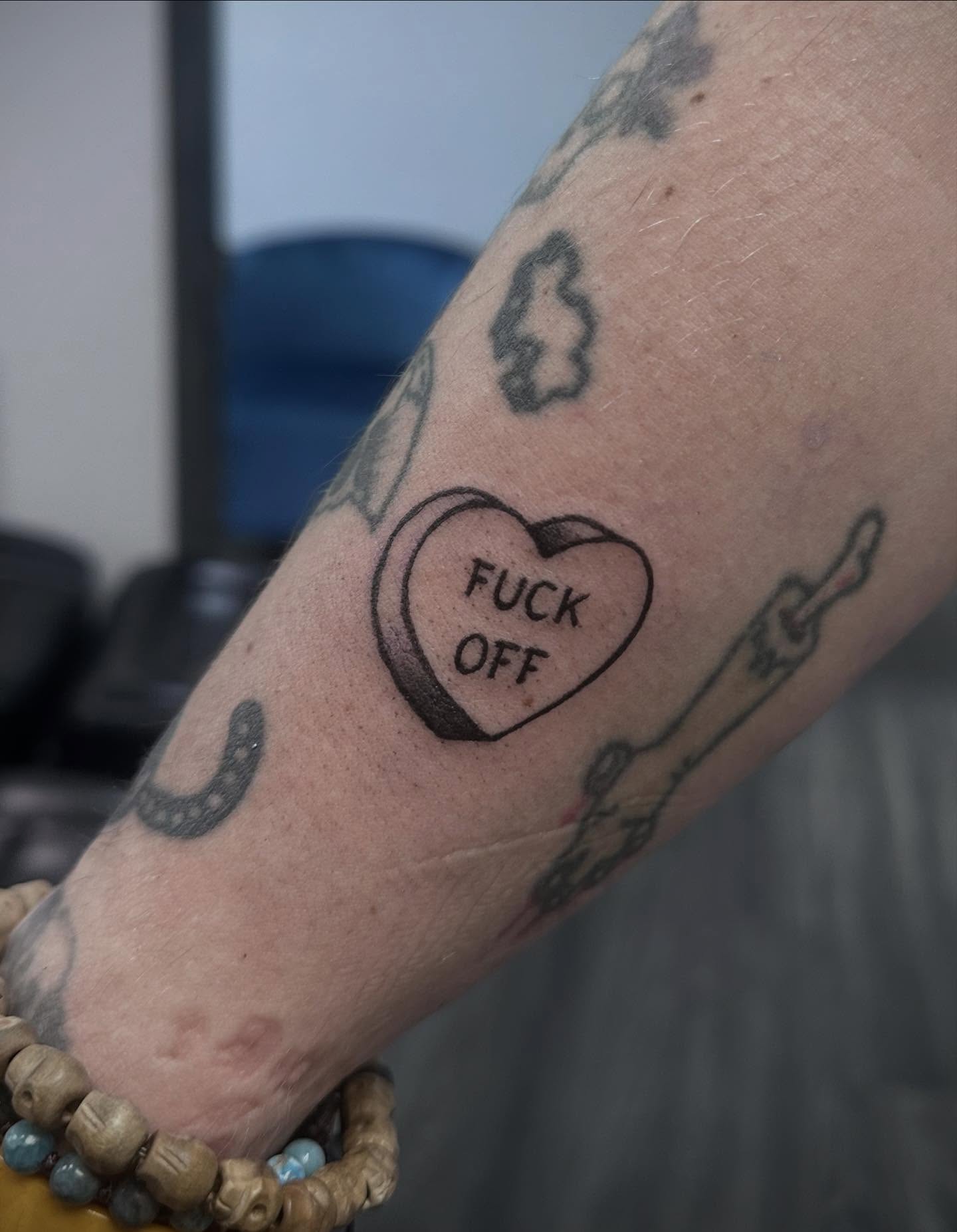 Heart with text black and grey tattoo on the forearm by Bell