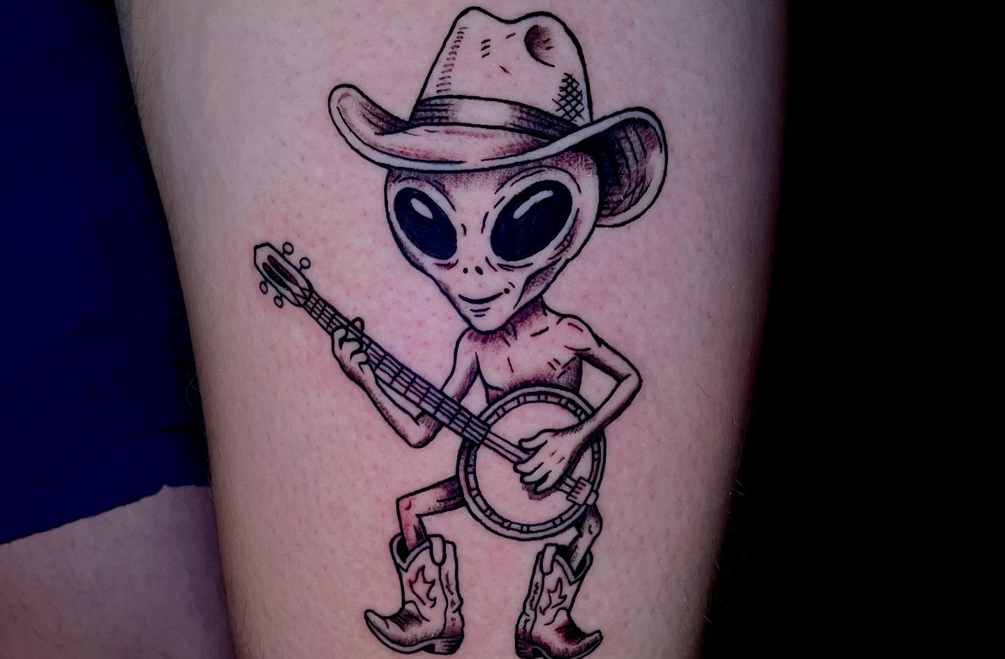 Alien playing banjo black and grey tattoo on the thigh by ๐ท๐ซKevan๐๐ท