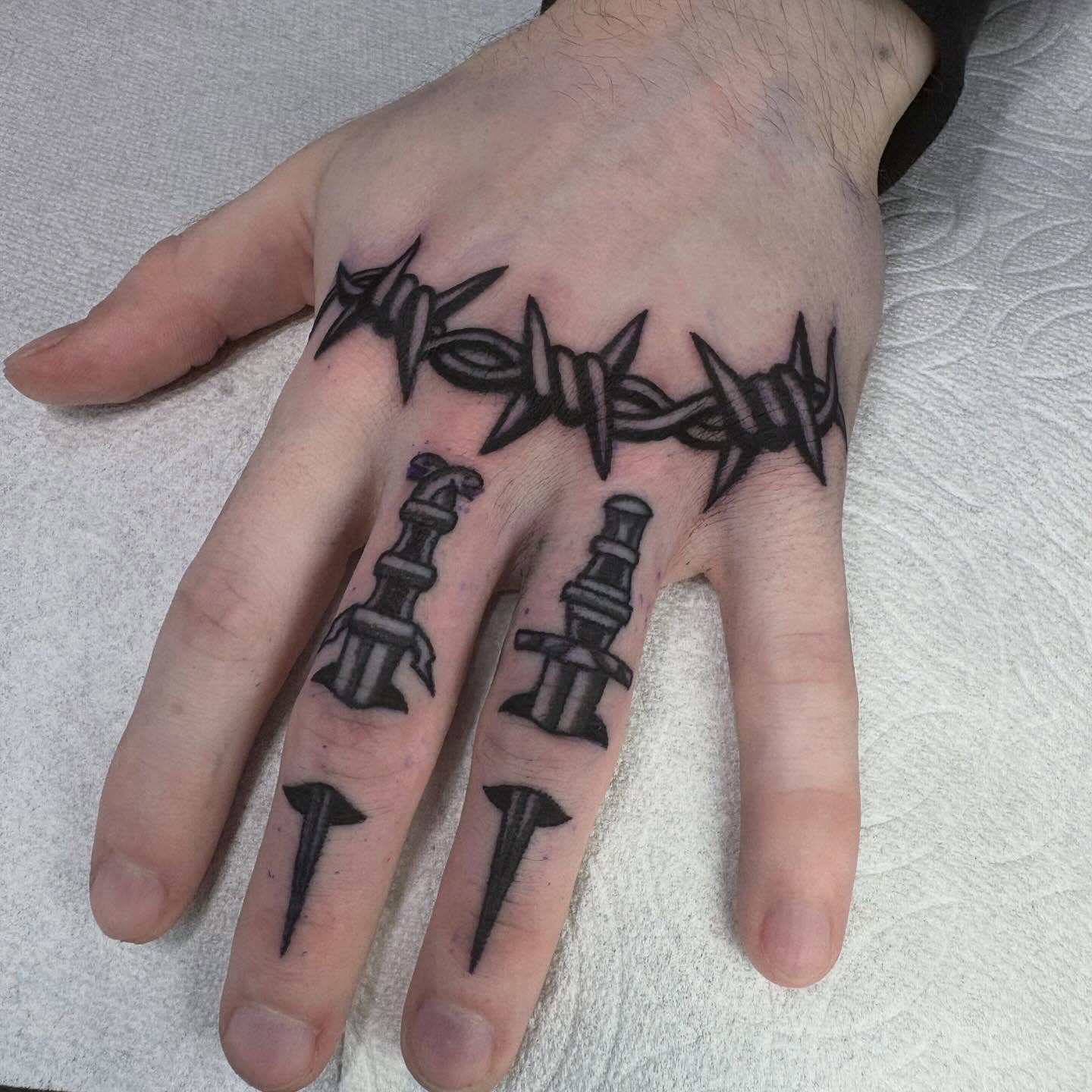Barbed wire and nails black and grey tattoo on the hand by Lindsey Cam Van
